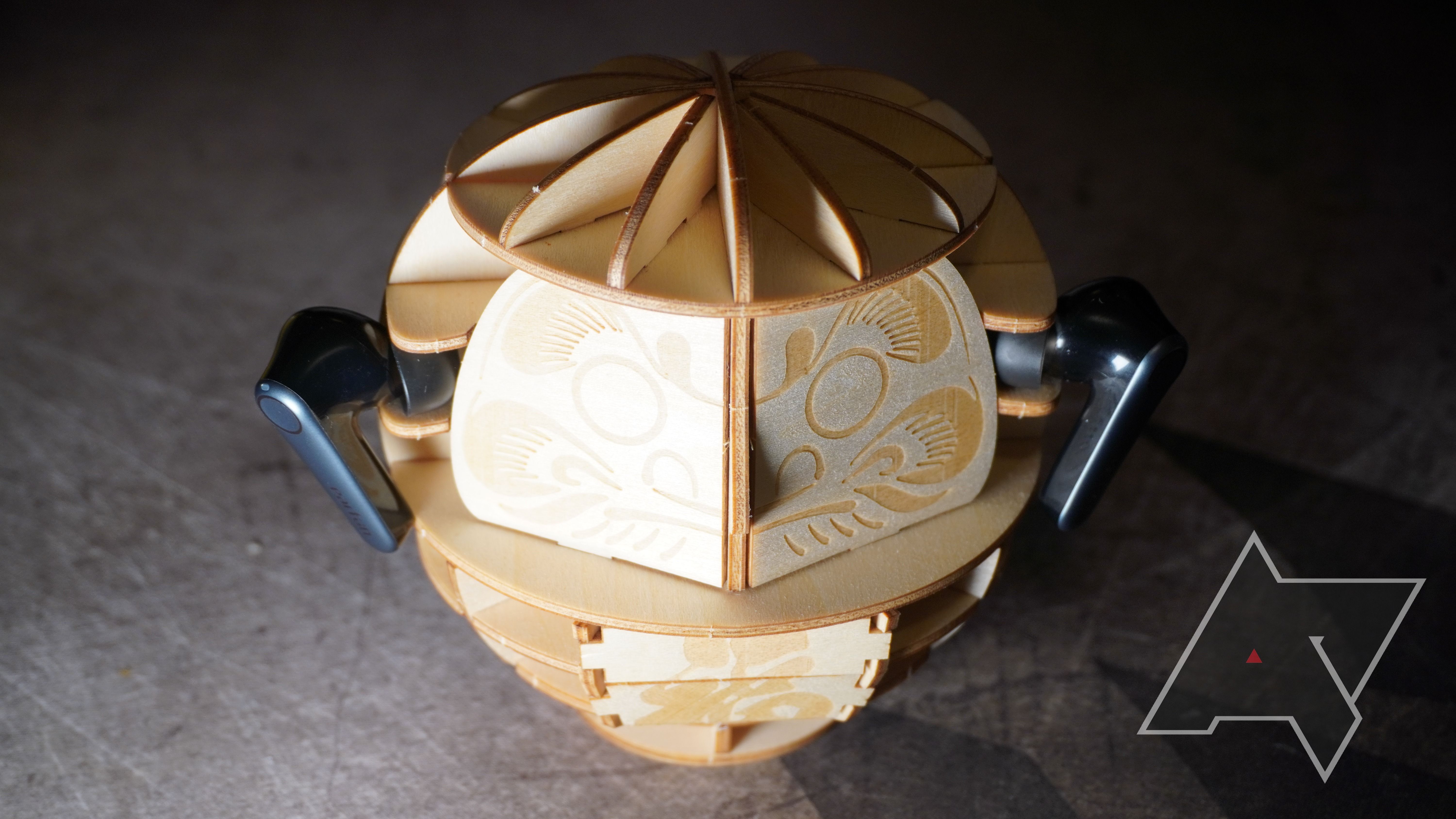 Fones de ouvido EarFun Air Pro 3 em um Daruma de madeira