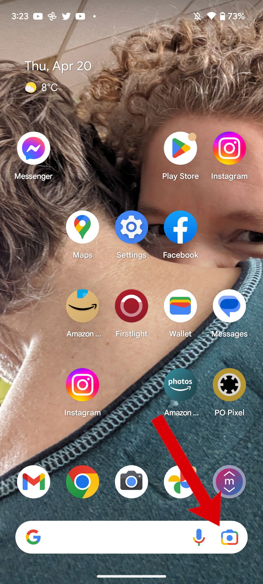 A screenshot of the Android home screen with an arrow pointing to the Google Lens icon.