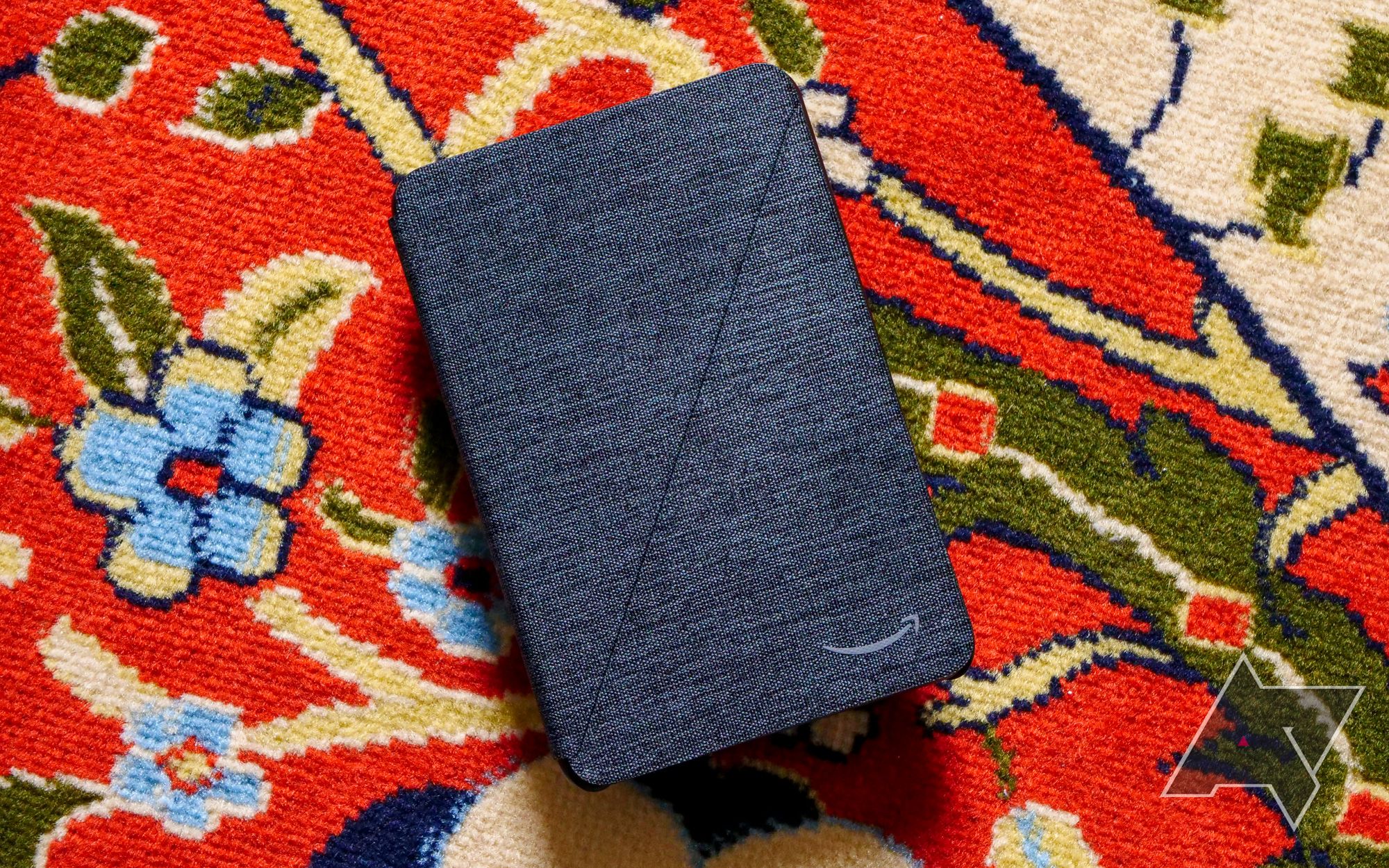 An Amazon Fire 7 in a cover case resting on a colored background