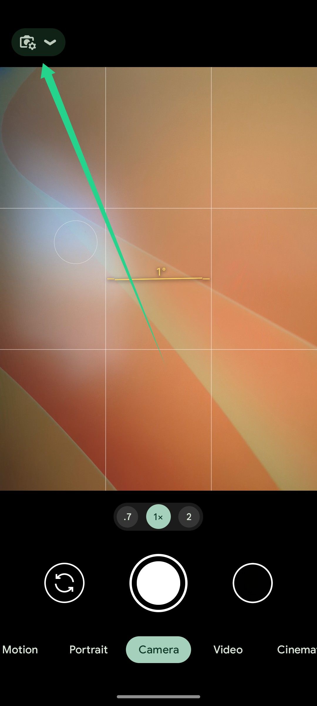 A Pixel phone's camera viewfinder with an arrow pointing to the settings icon.