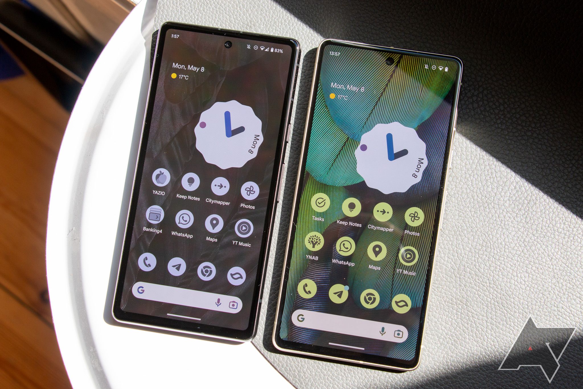 The Google Pixel 7a and Pixel 7 next to each other, both showing the home screen with themed icons