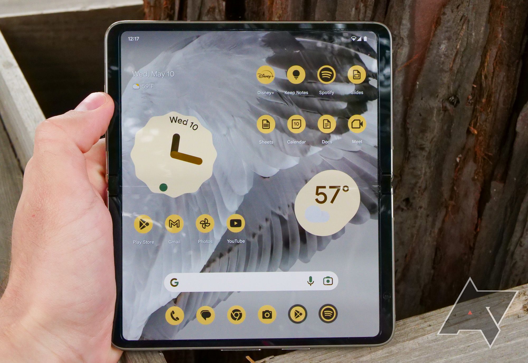a person holds a Google Pixel fold in tablet mode. The display is illuminated. 