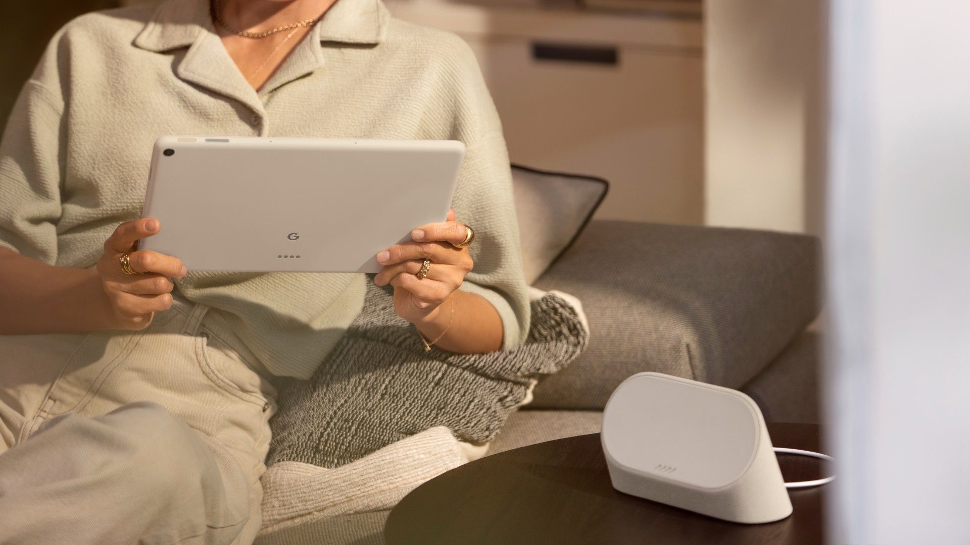A woman holds a tablet in a neutral interior.