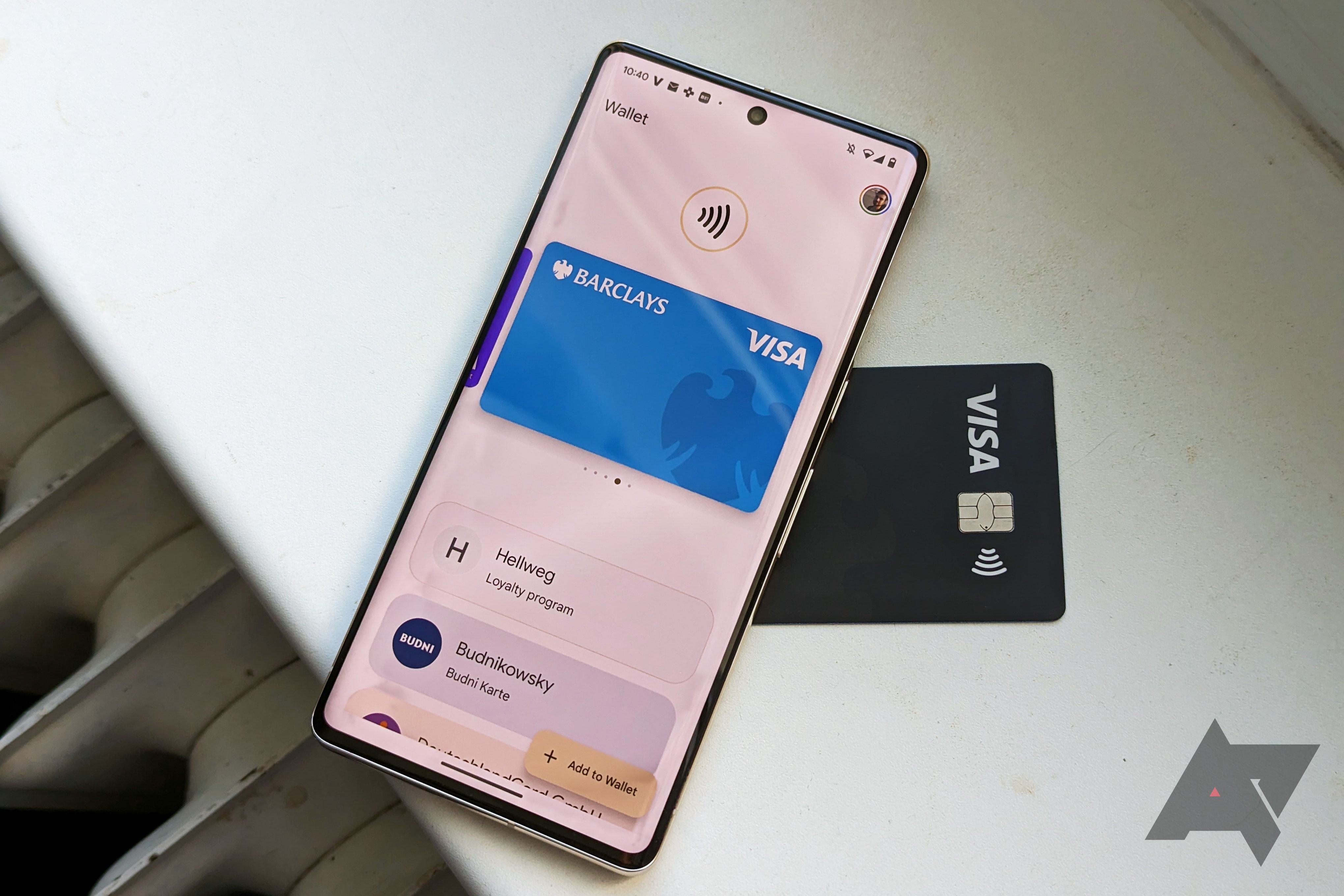 A Pixel phone displaying Google Pay with a blue Visa card while the phone rests on top of an actual black visa card.