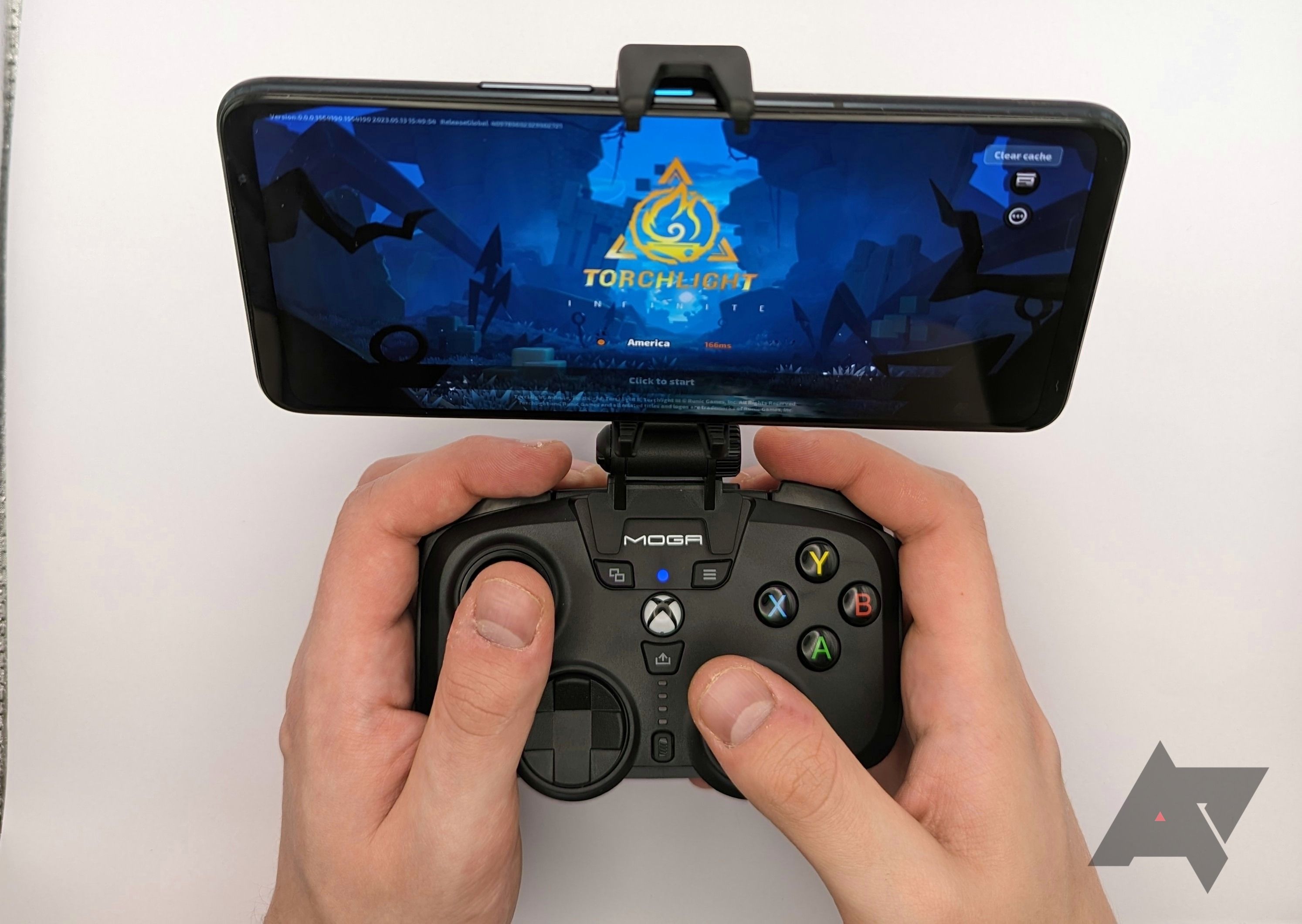 hands holding game controller with attached phone