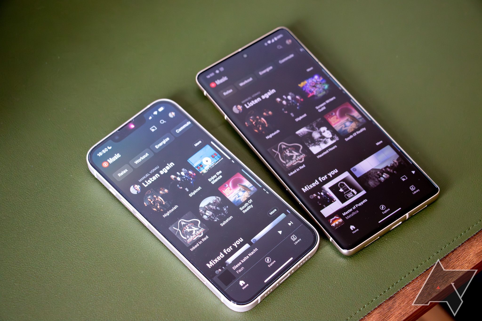 An Apple iPhone 13 lies next to a Google Pixel 7 Pro on a green surface, with the YouTube Music app opened on both of them