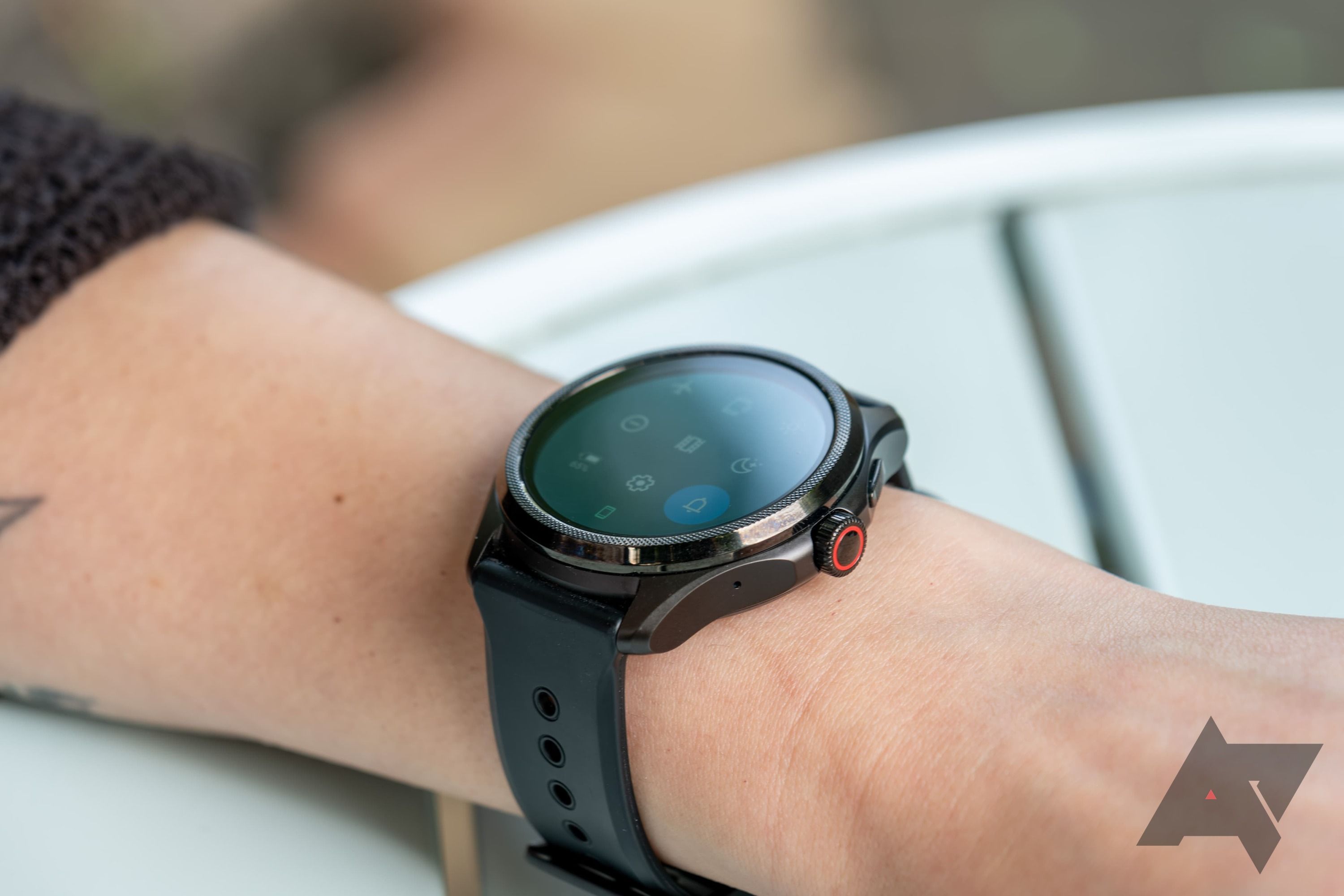 A Mobvoi Ticwatch Pro around an arm that's resting on a table outside