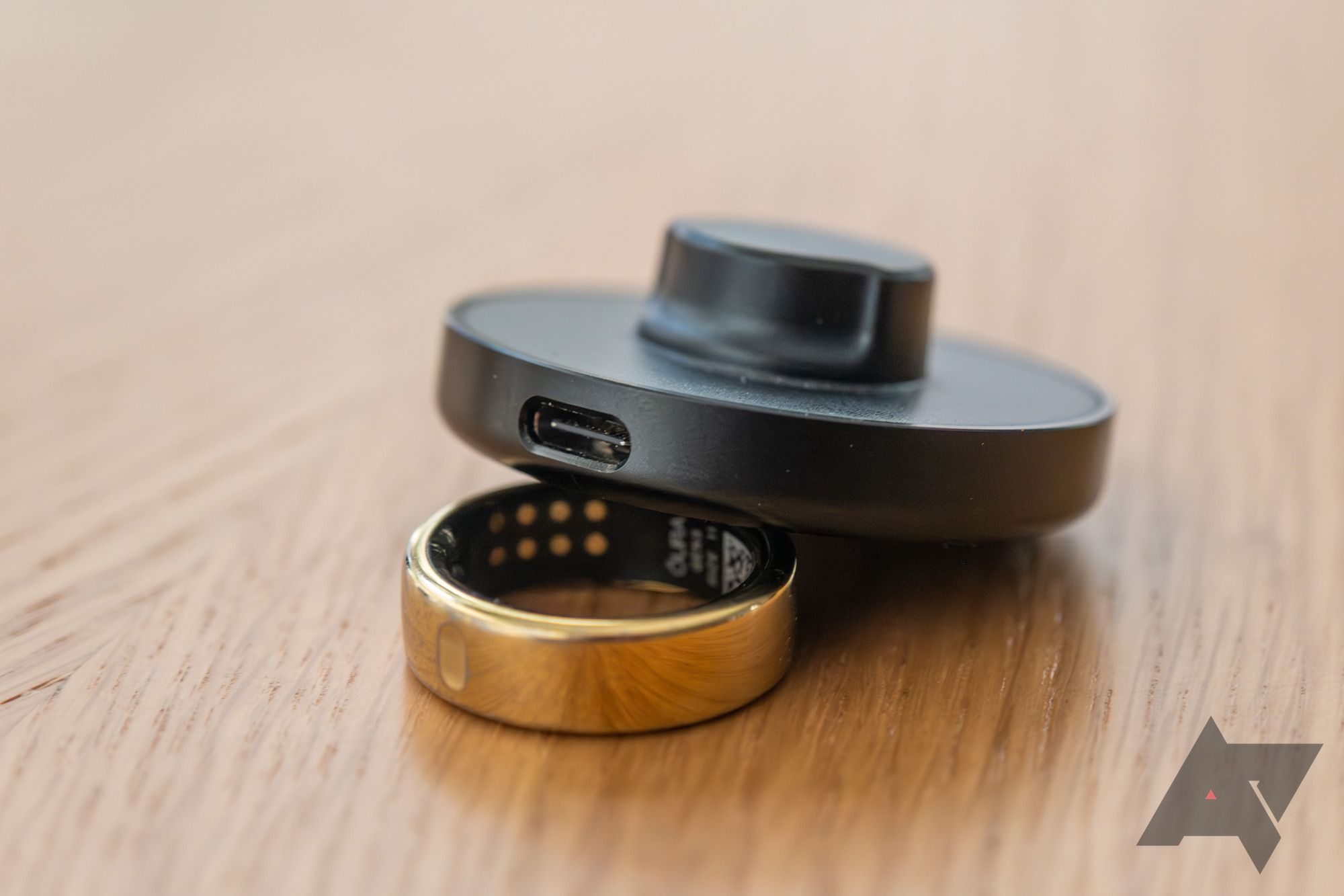 A gold smart ring and its charger.