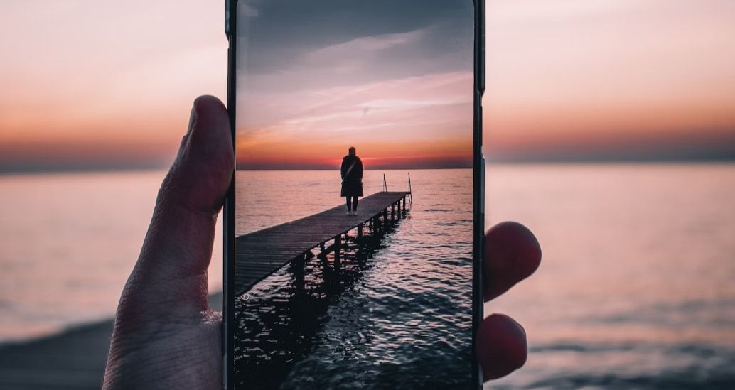 Person taking a photo of a pier with negative space surrounding the subject