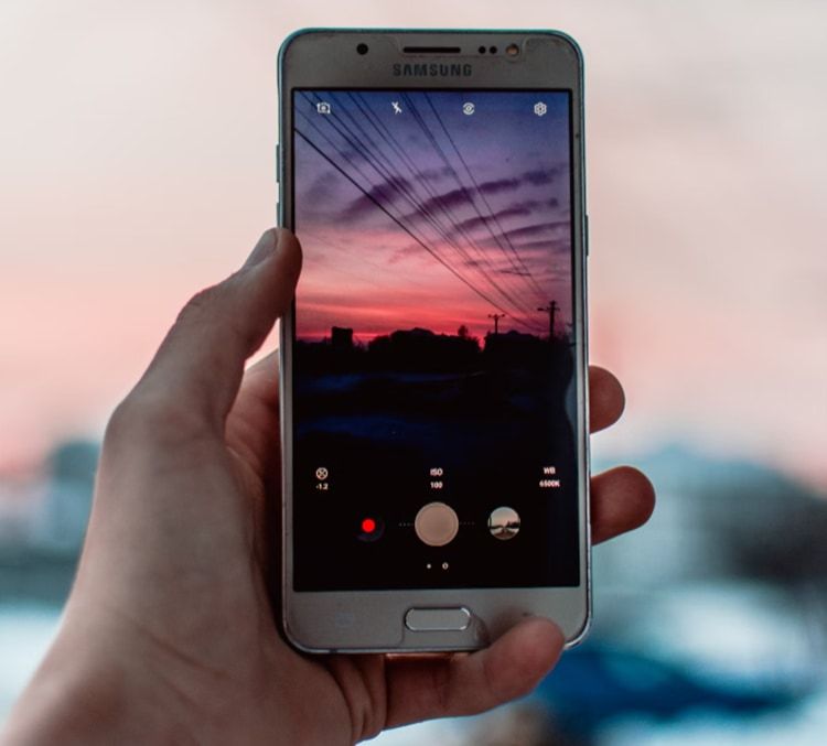 Person taking a picture of the sunset with mobile phone hero image