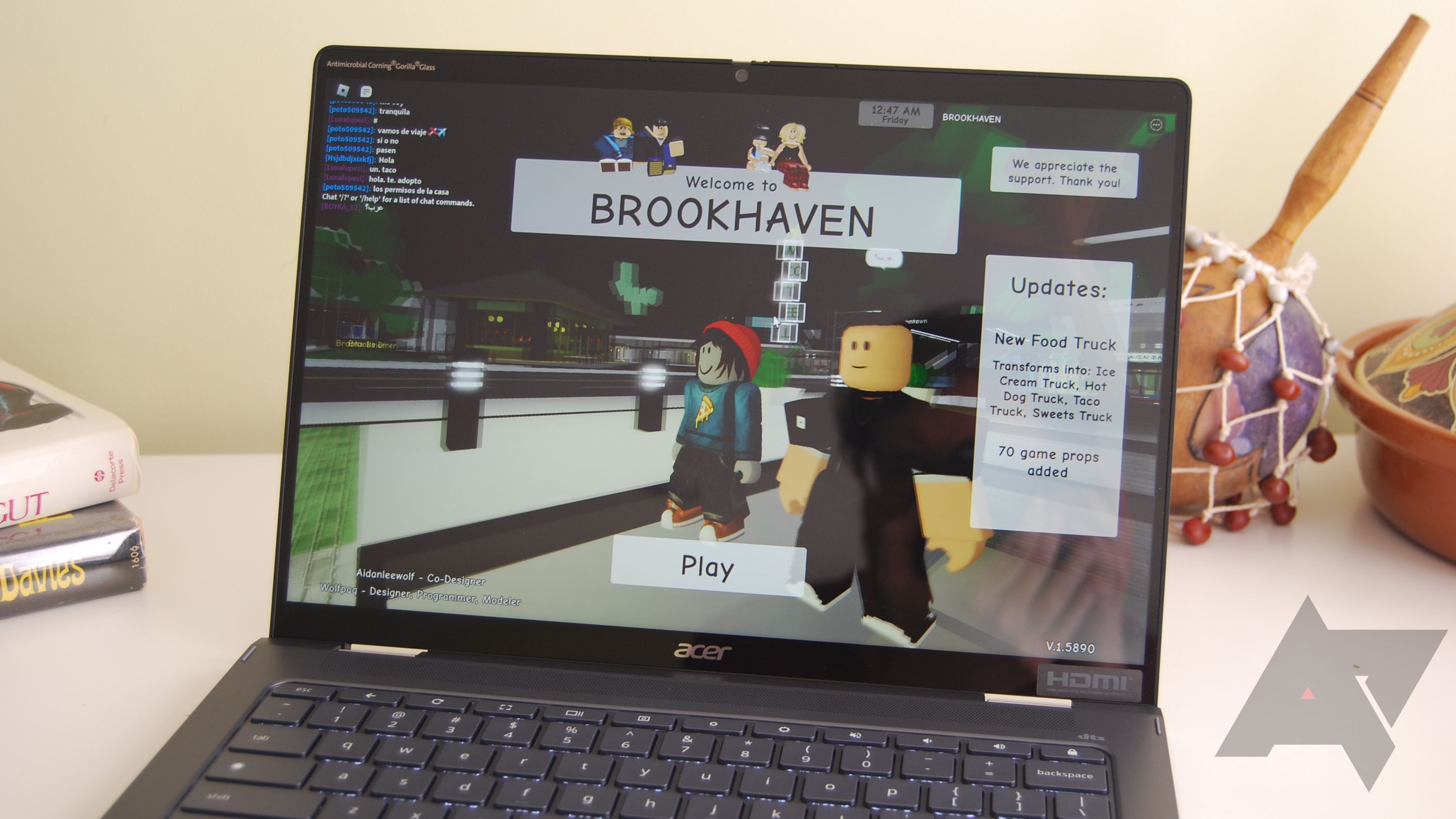 A black Chromebook sits on a white desk. The Roblox app is open on the screen.