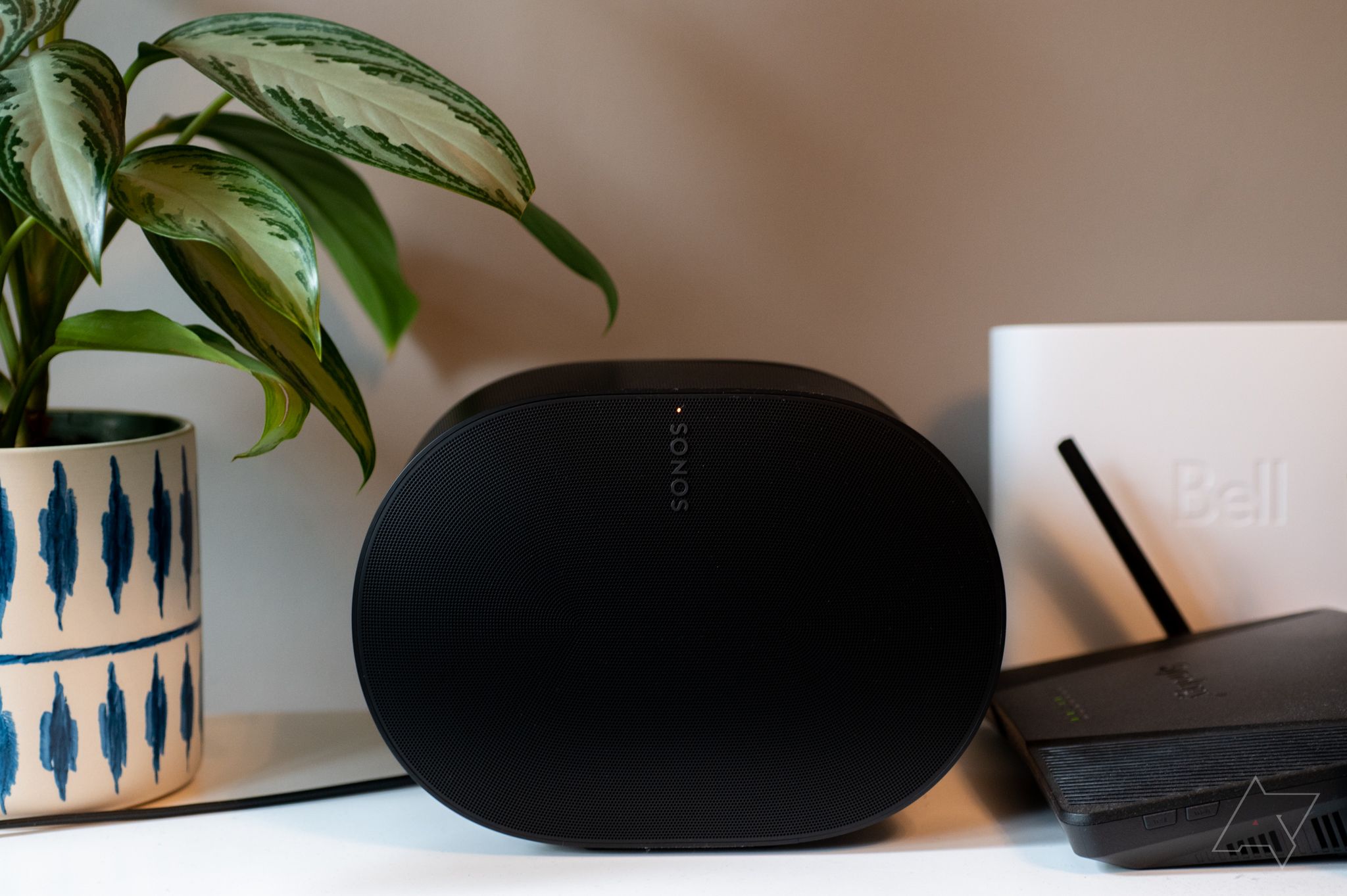A Sonos Era 300 sitting next to a plant and a router