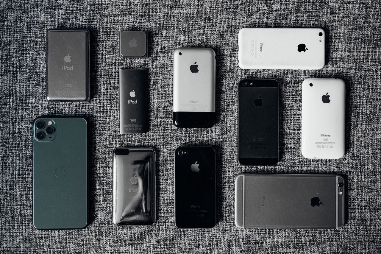 A number of iPhones and iPods neatly laid out in a chaotic pattern on a gray backdrop