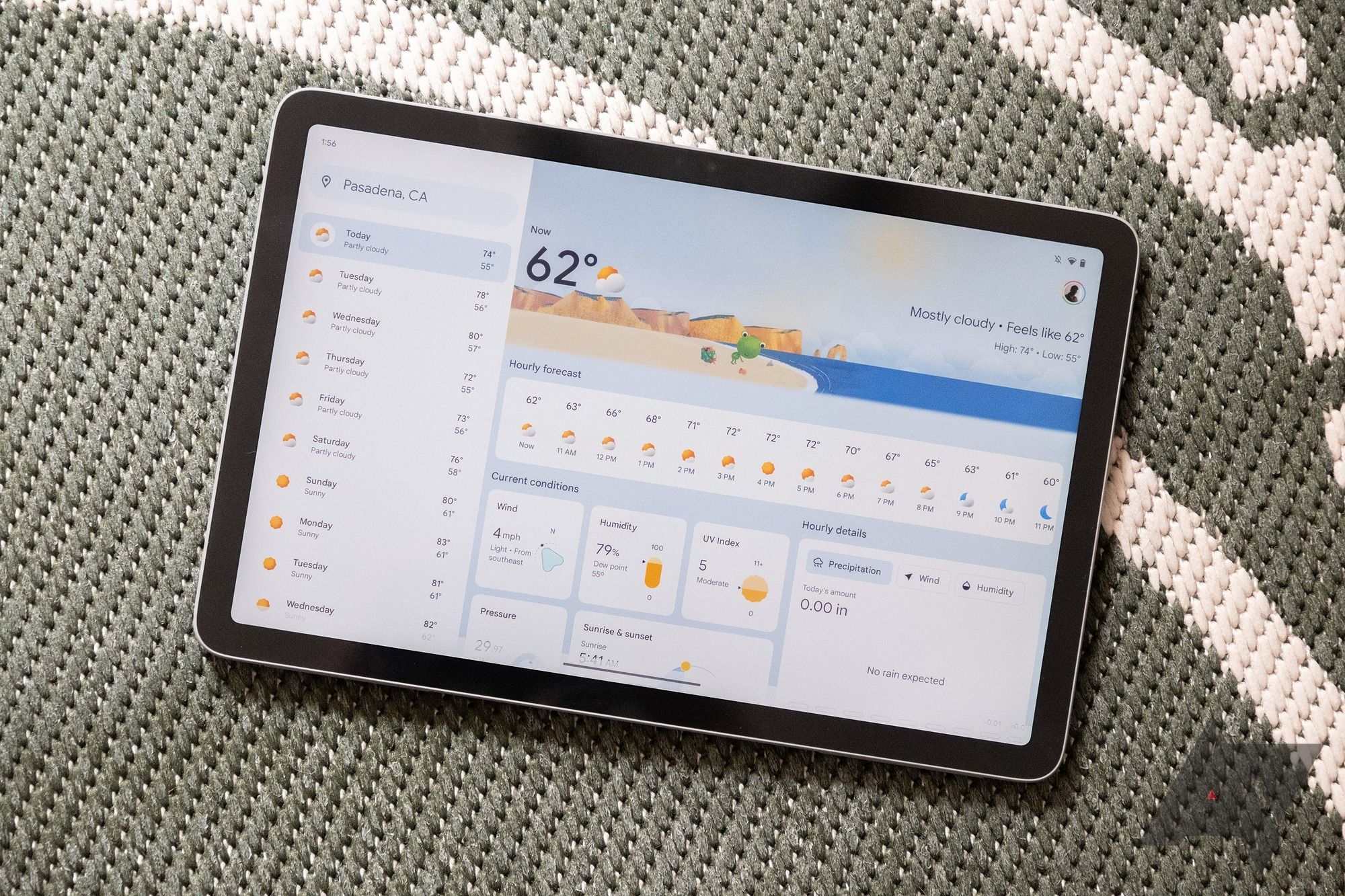 google pixel tablet resting on grey fabric showing weather app