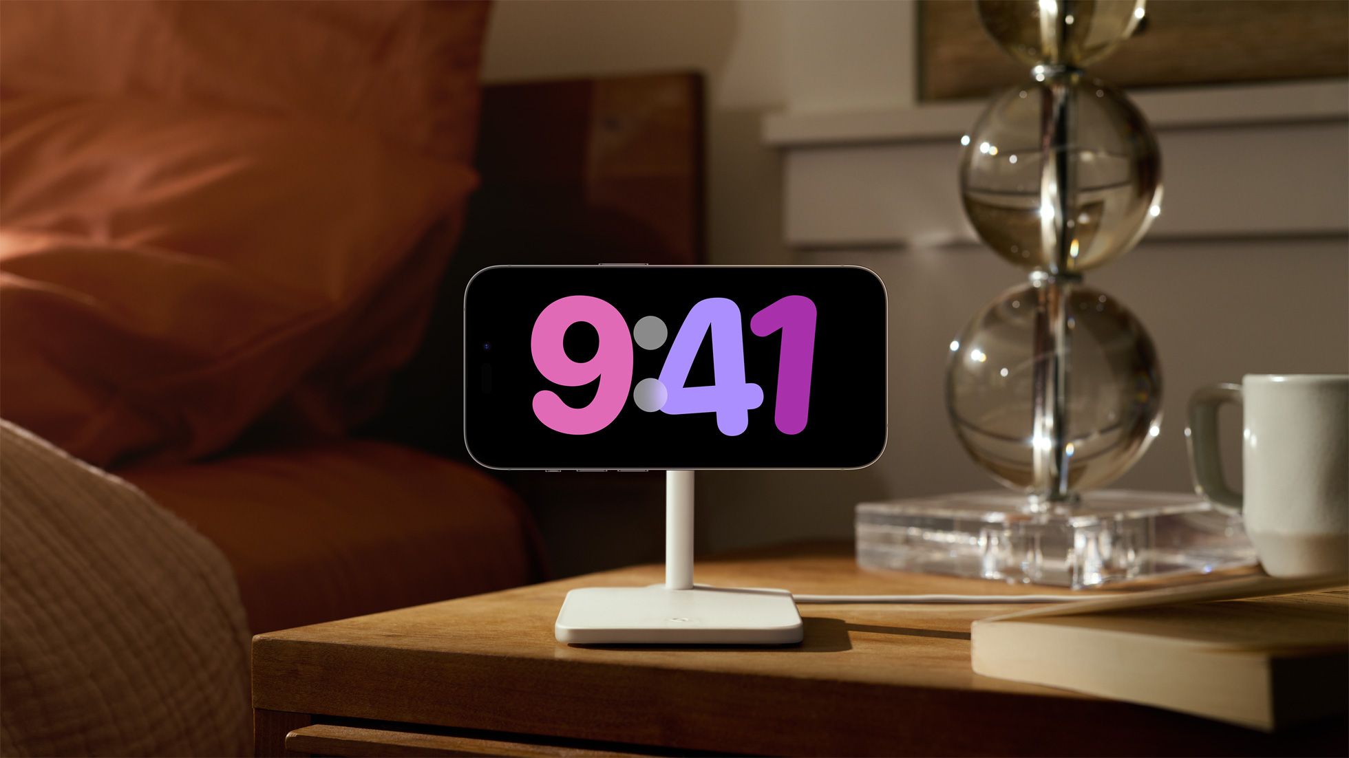 An iPhone connected to a MagSafe charging stand with a colossal clock face proven using StandBy