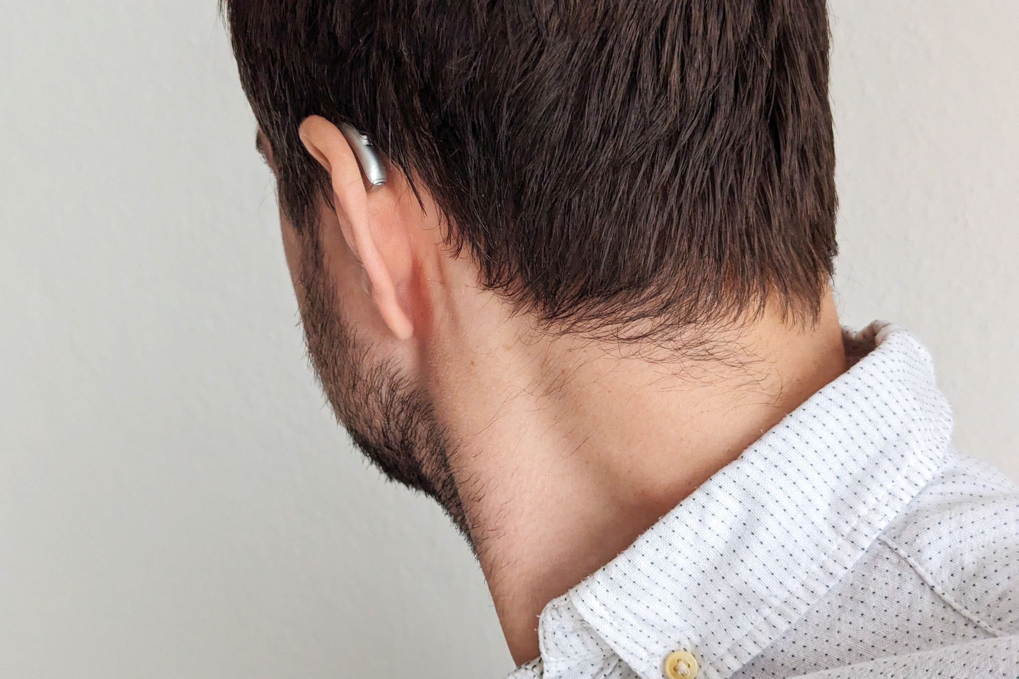 A man is facing away from the camera, with a sliver Phonak hearing aid visible behind his ear