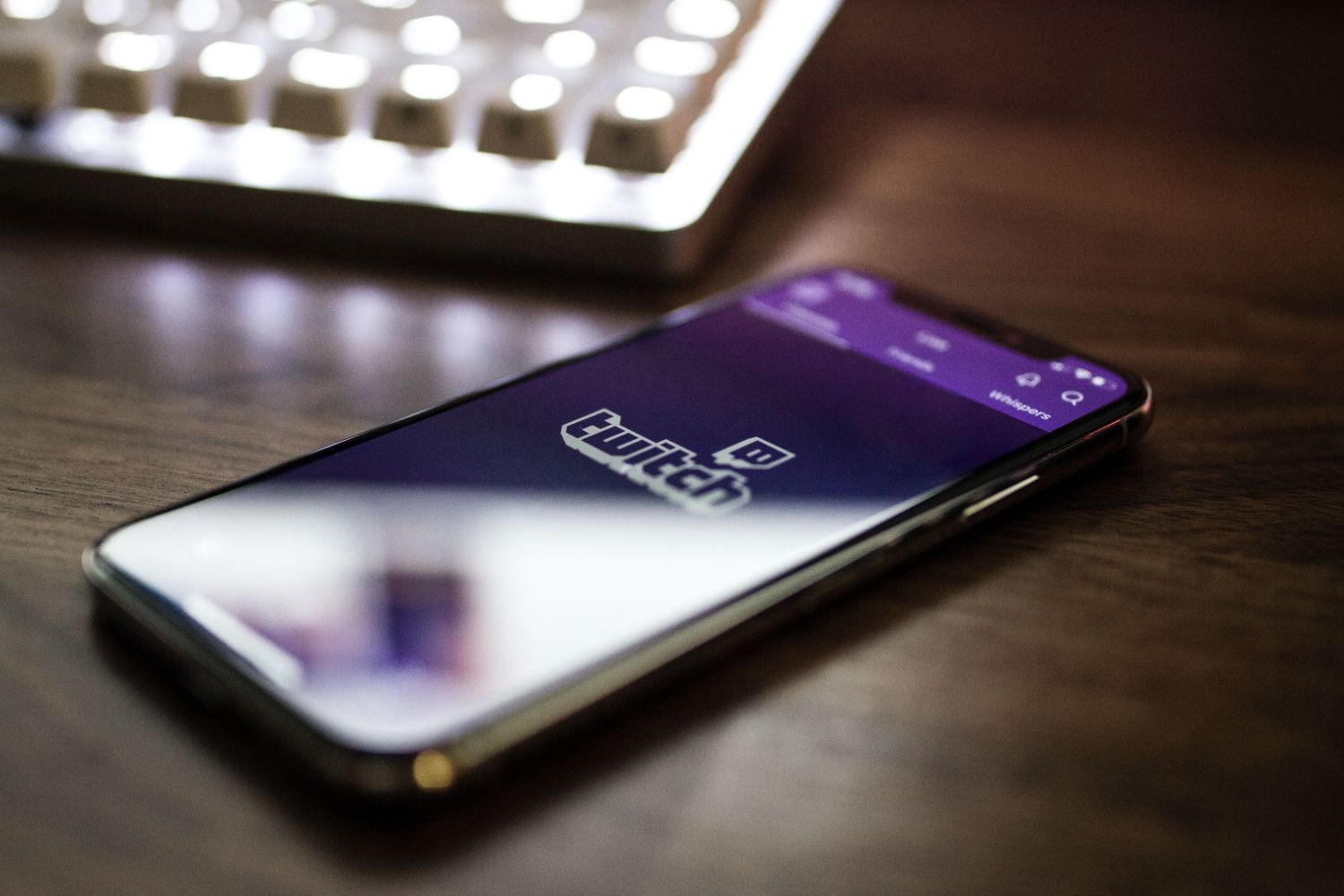 Twitch logo on mobile laying on a brown desk