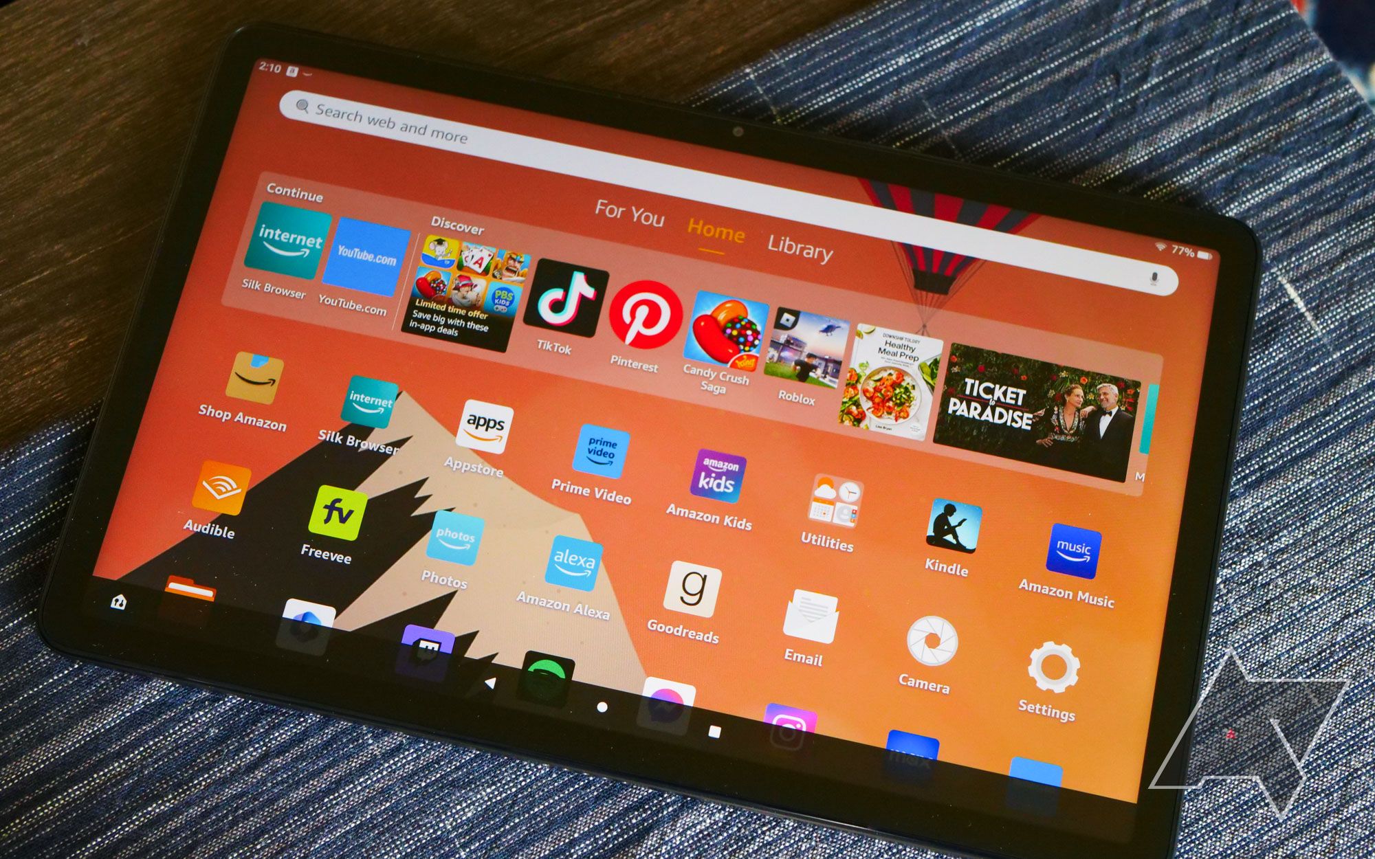 The Amazon Fire Max 11 tablet resting on top of a table with the apps list open.