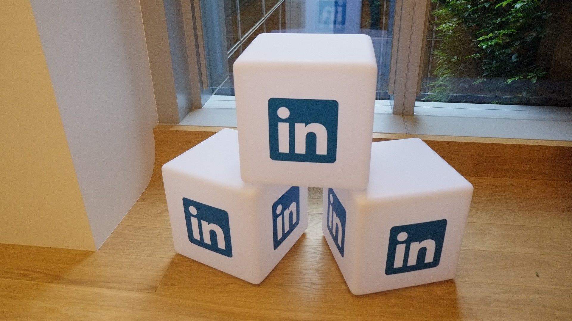 Three white blocks with the LinkedIn logo stacked on a wooden floor