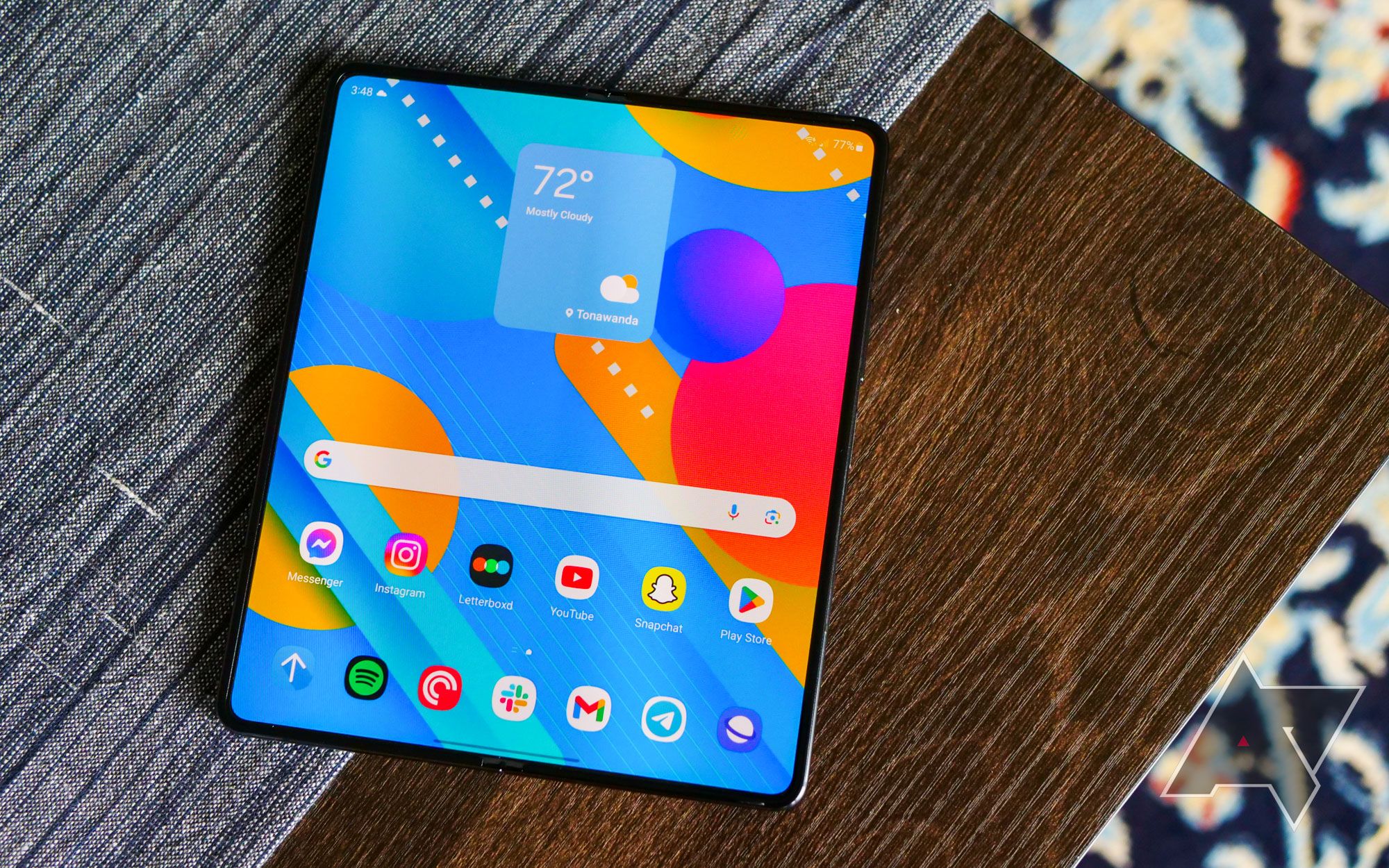 A photo of the Samsung Galaxy Z Fold 5 open on a table top displaying the home screen