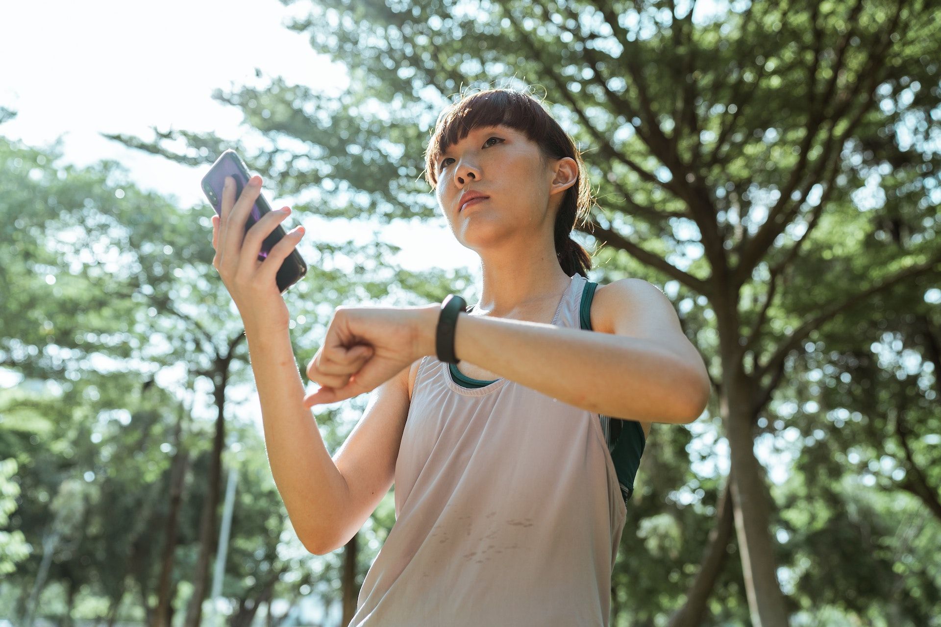 A person stops during their workout to check their heart rate using a phone and smartwatch.
