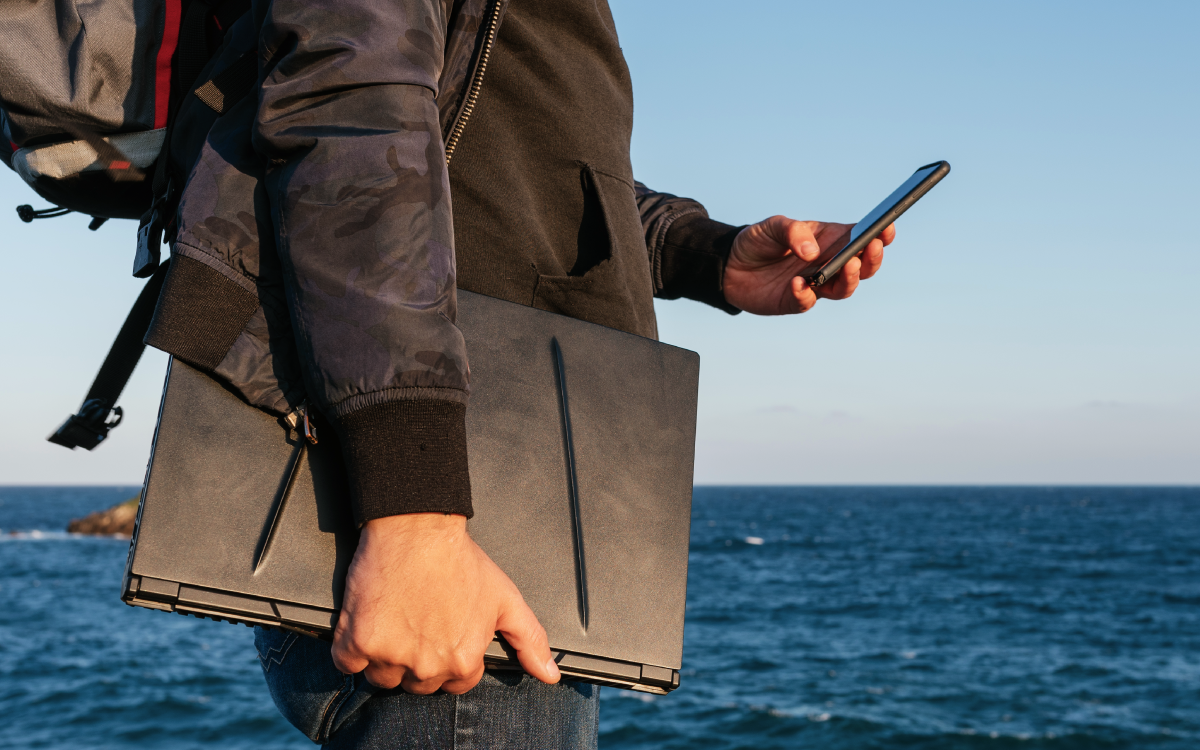 Male traveler using his phone by the sea