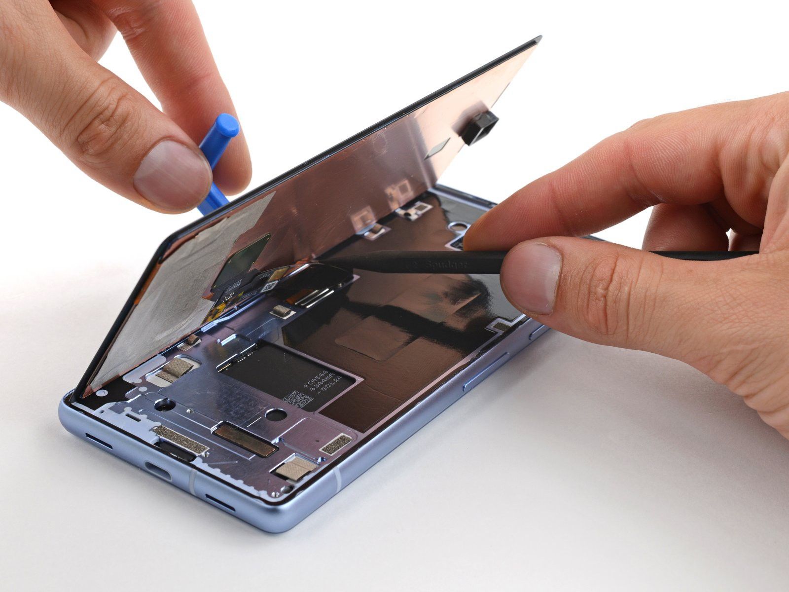 A Pixel 7a being repaired with it's screen being removed from the body of the phone