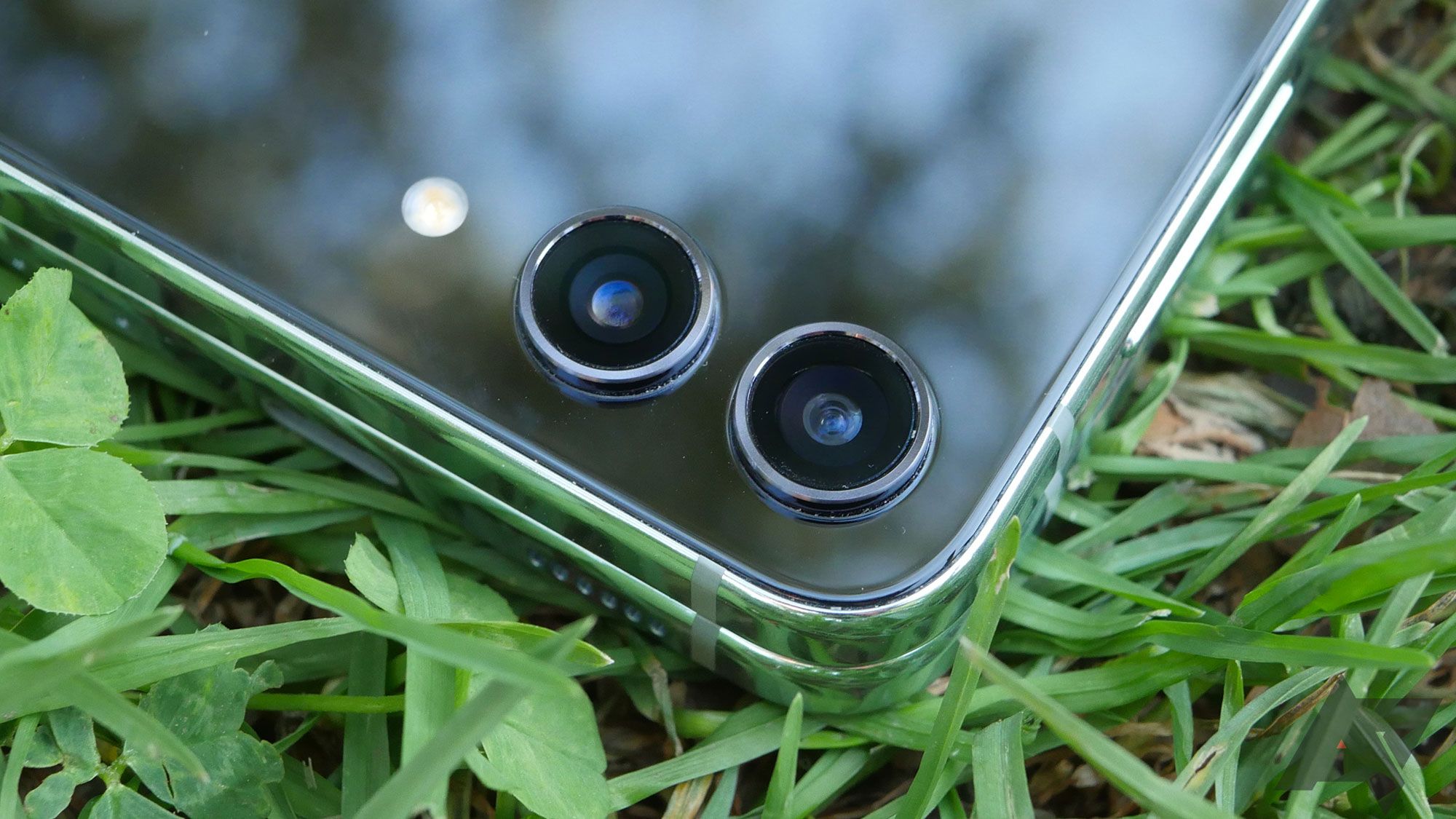 A Samsung Z Flip 5 with its external camera lenses visible sitting on some grass