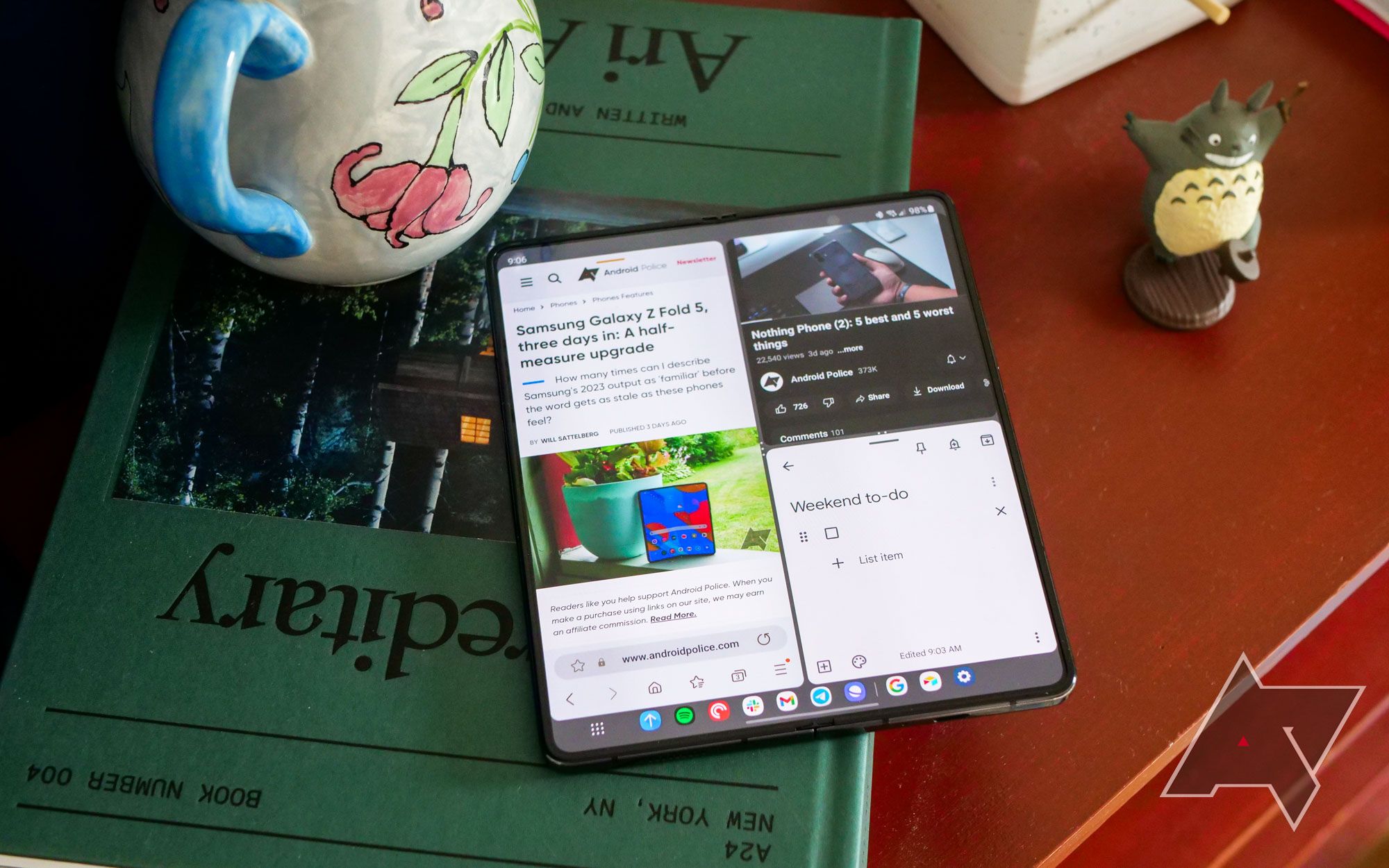 A Samsung Galaxy Z Fold 5 laying open on a green bok on top of a desk.