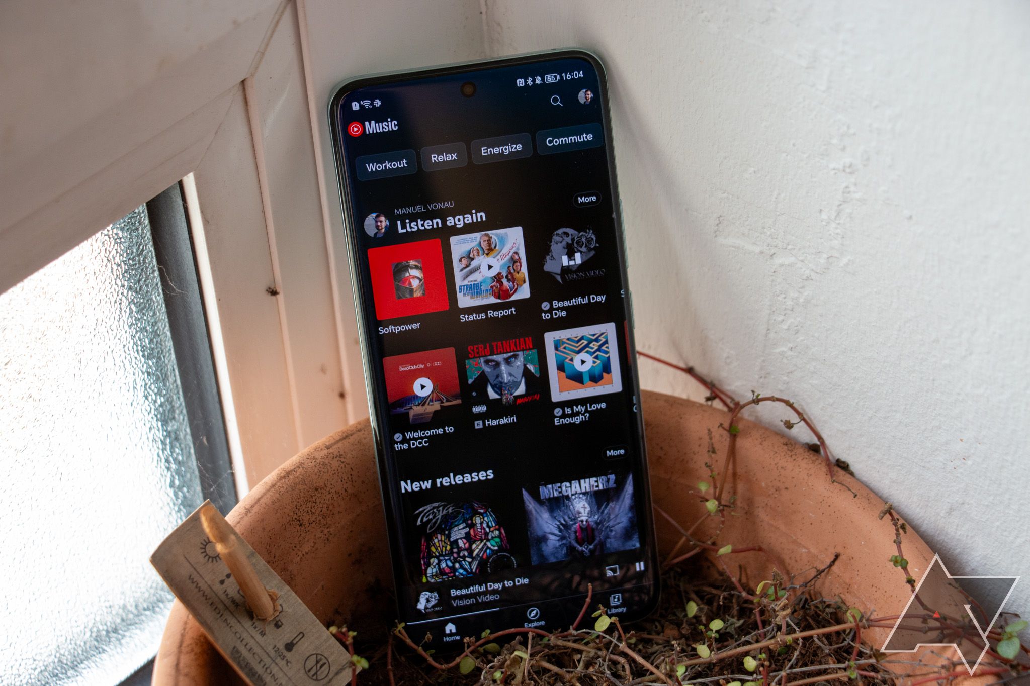 The YouTube Music home screen on an Android phone resting in a clay pot.
