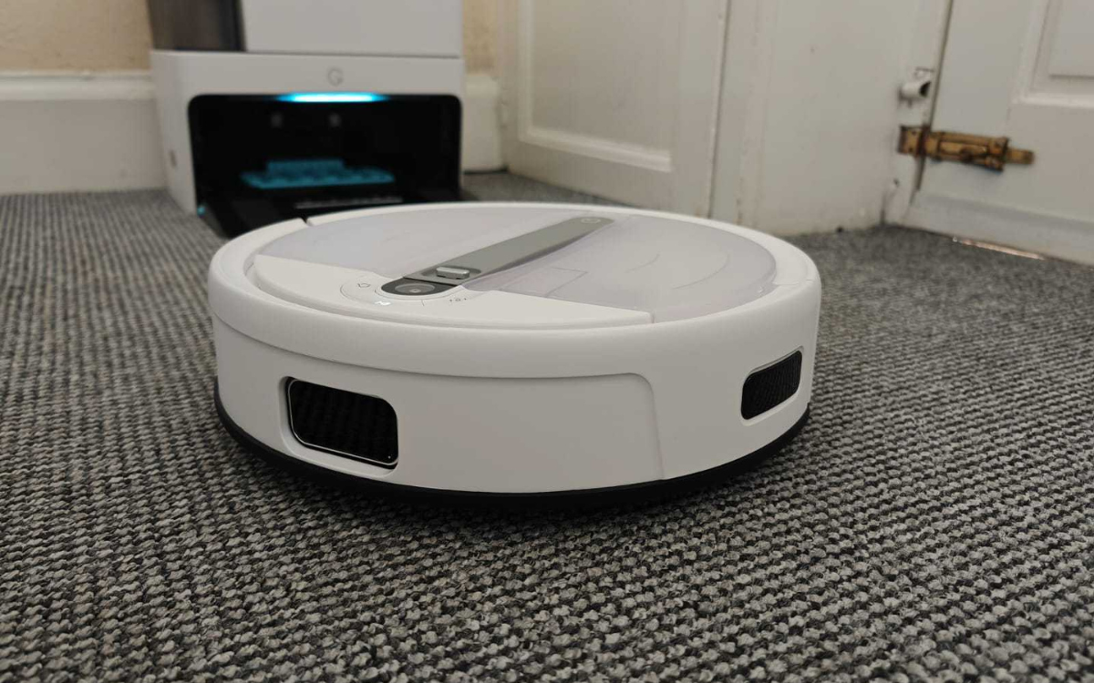 Yeedi Dice robovac cleansing carpet with docking station in background