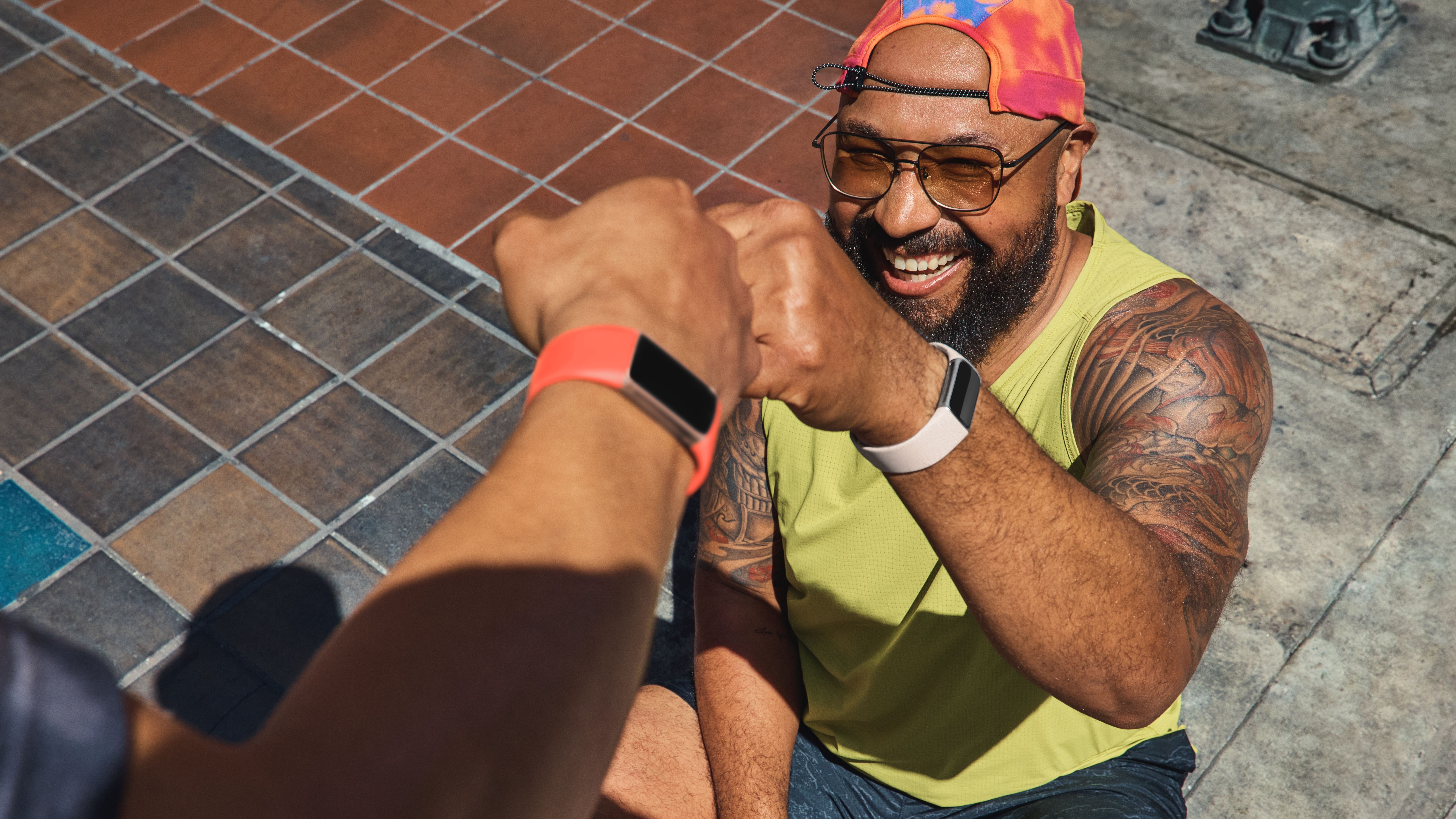 Two people share a fist bump with the Fitbit cCharge 6 on their wrists 