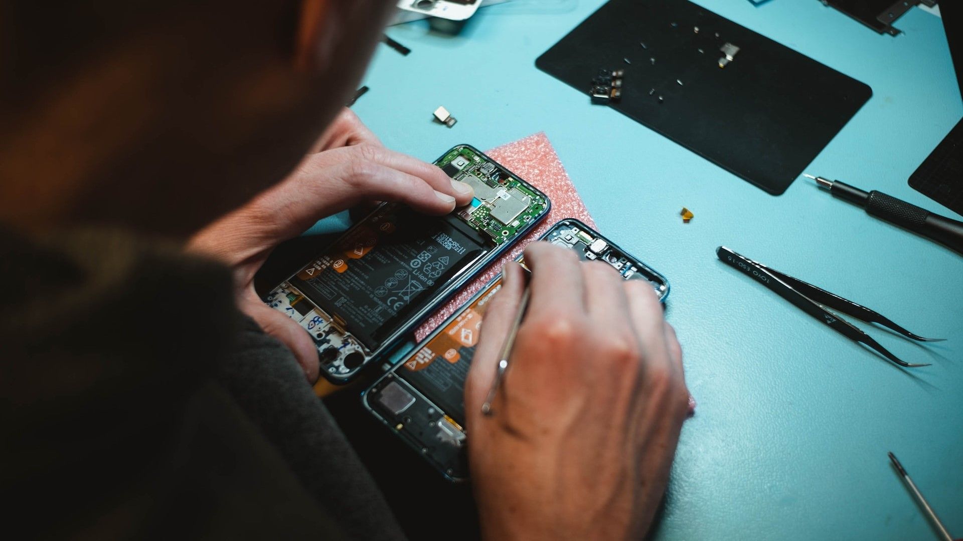 An particular person is disassembling a cellphone.