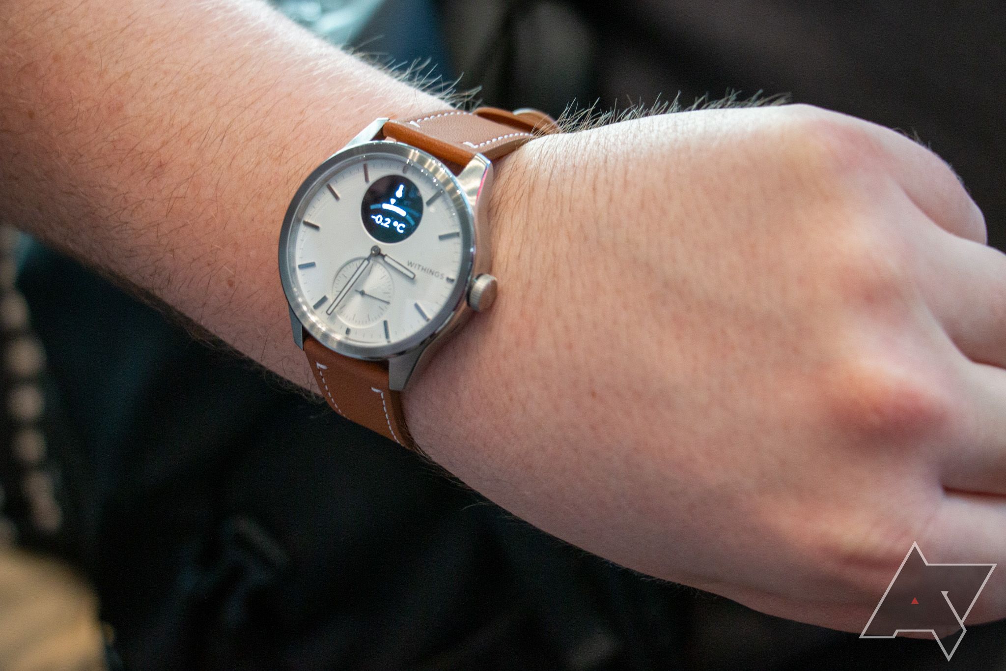 A Withings Scanwatch with a tan band getting used on a wrist