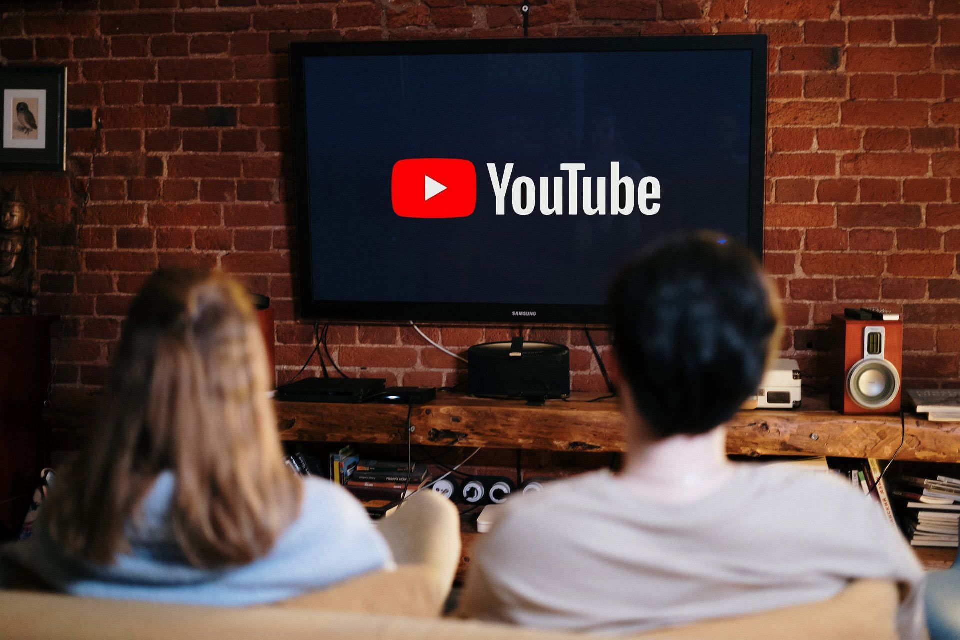 Two people are looking at a television with the YouTube logo displayed. 