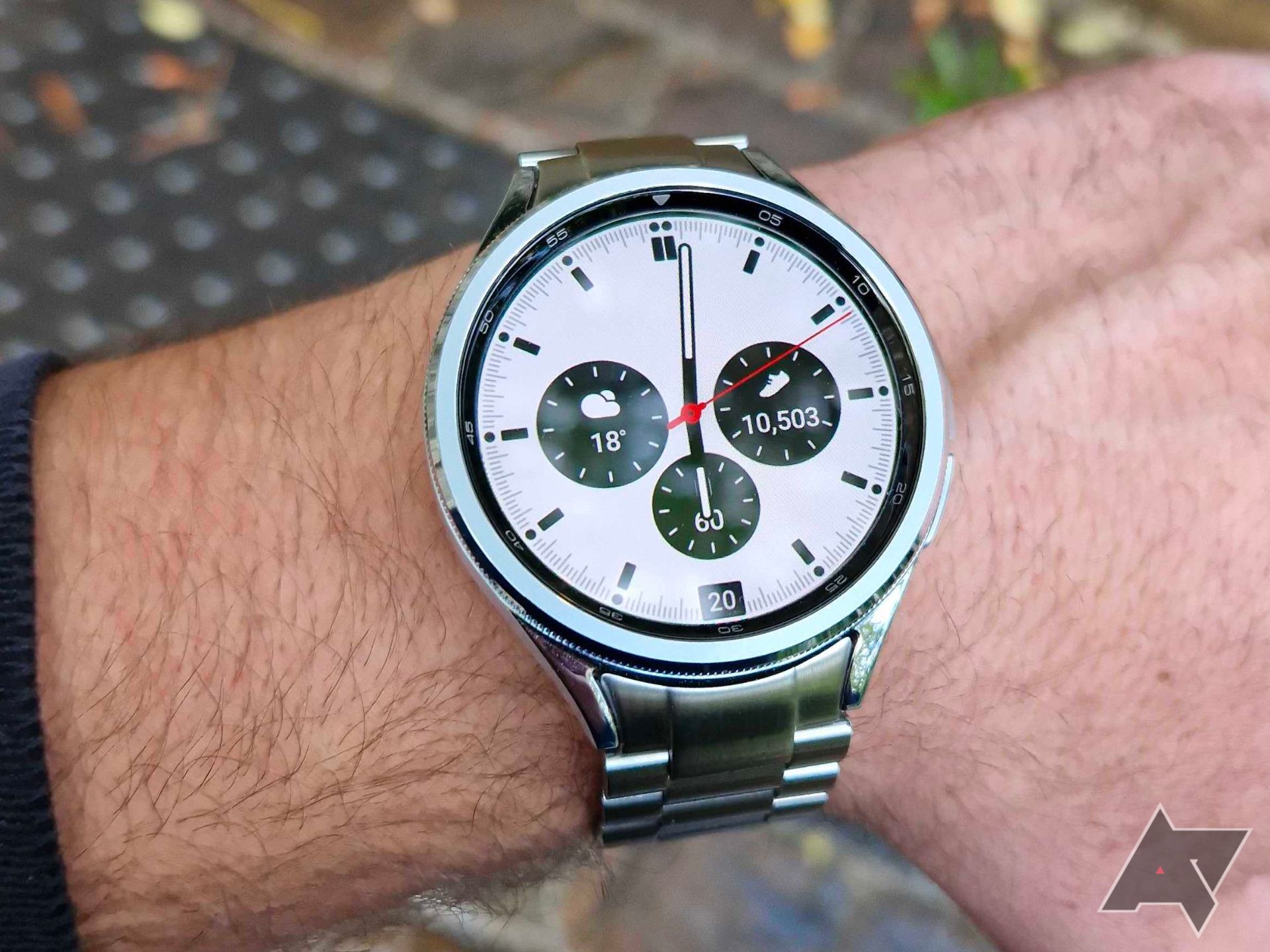 A picture of a man's hand wearing a Samsung Galaxy Watch6 Classic, with leaves falling on the back