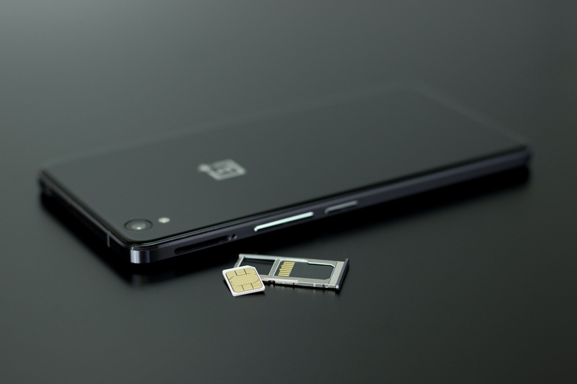 A black smart phone with a sim card slot removed and its nano sim on display.