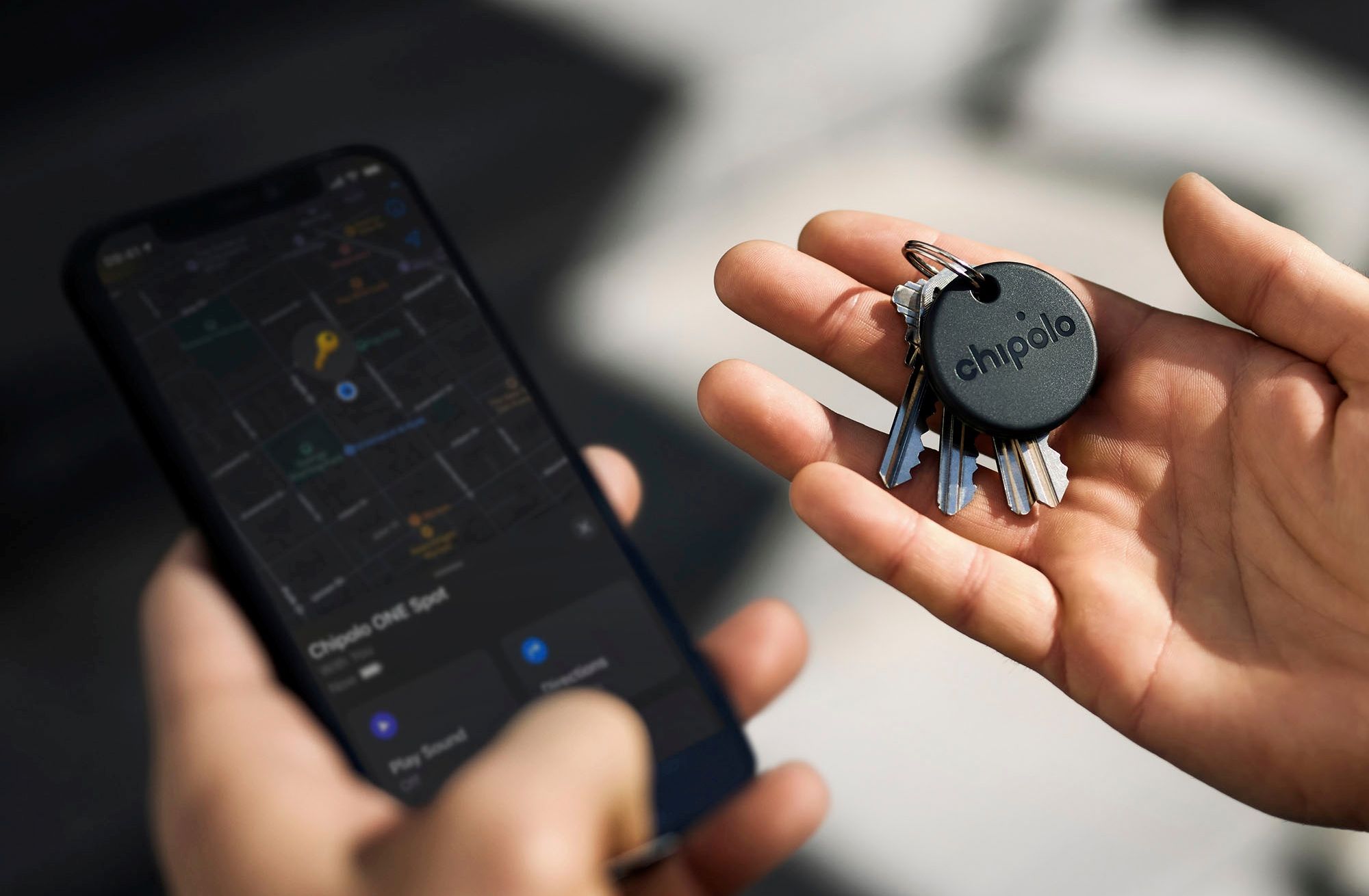 person holding a Chipolo one smart tag attached to keys and a smartphone