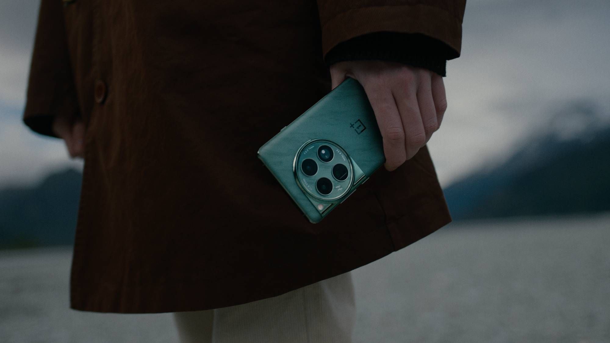 oneplus-12 held by a person in a brown coat