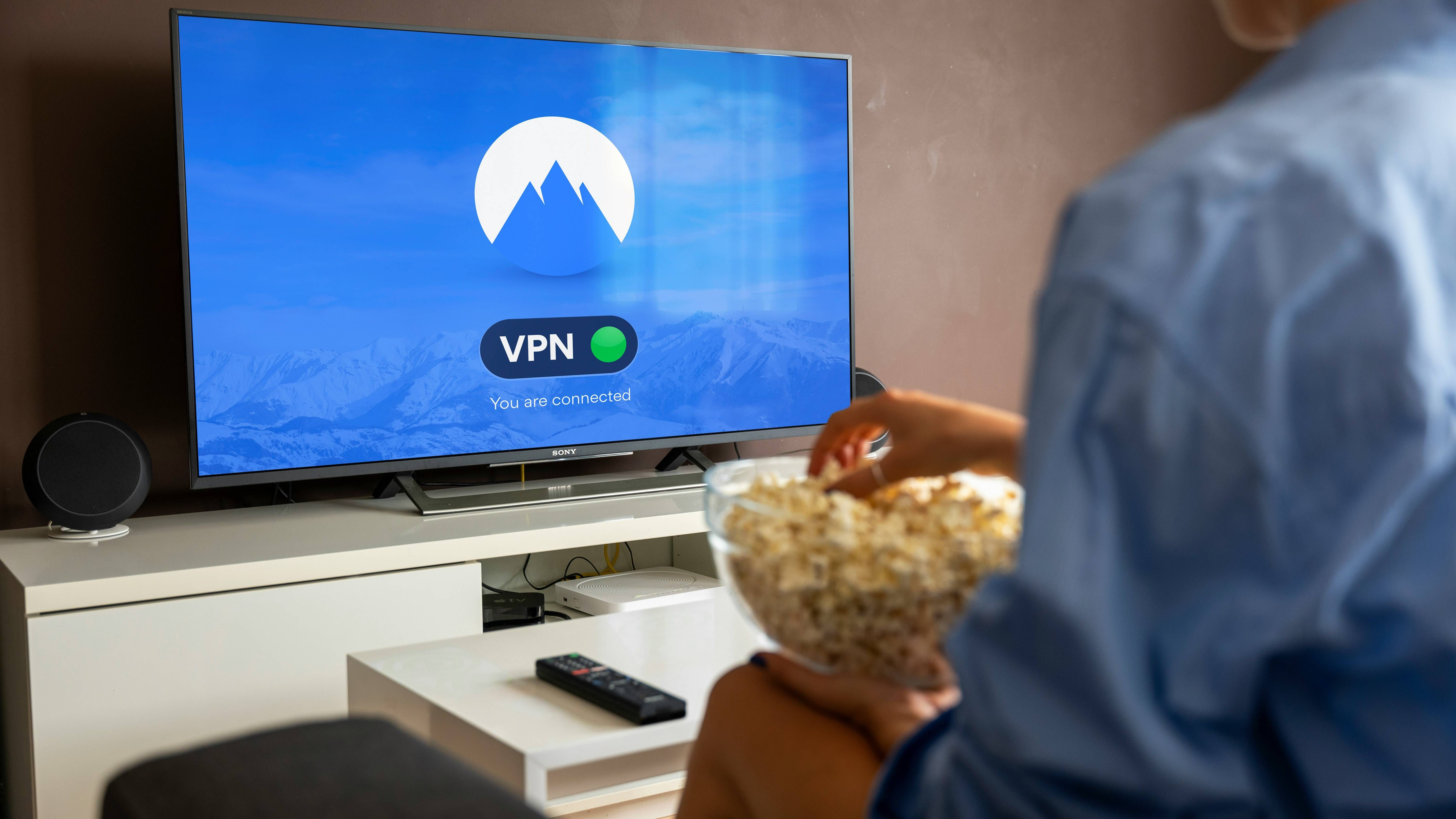 Person with popcorn watching black flat screen tv turned on display VPN connected