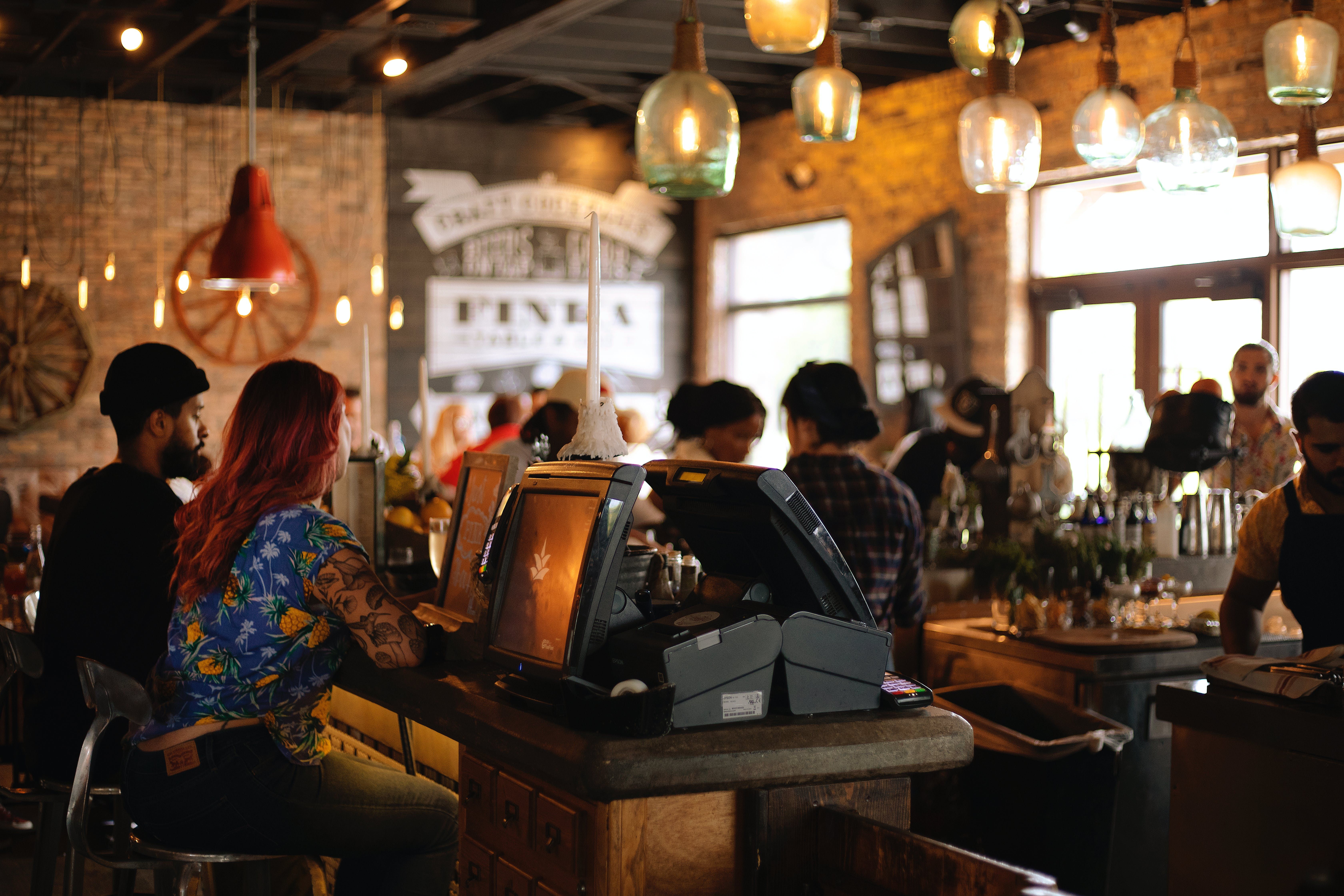 A restaurant filled with customers in the background and a payment terminal in the foreground.