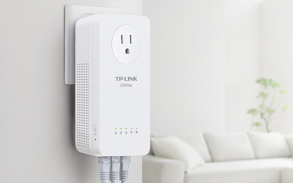 A TP-Link powerline adapter mounted on a white wall with a sofa in the background