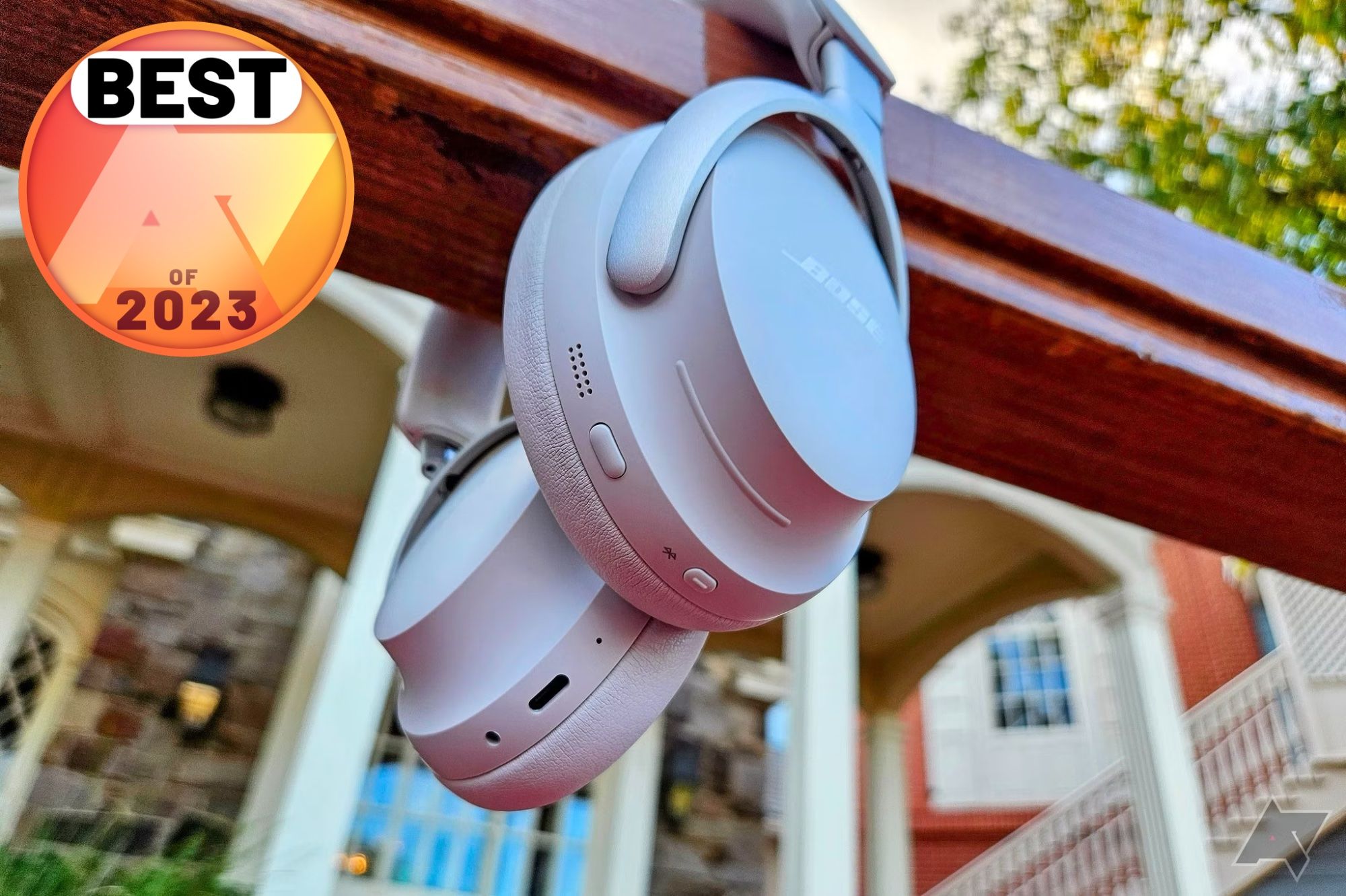 The Bose QuietComfort Ultra headphones hanging on handrail with a Best of 2023 Android Police badge in the top left corner