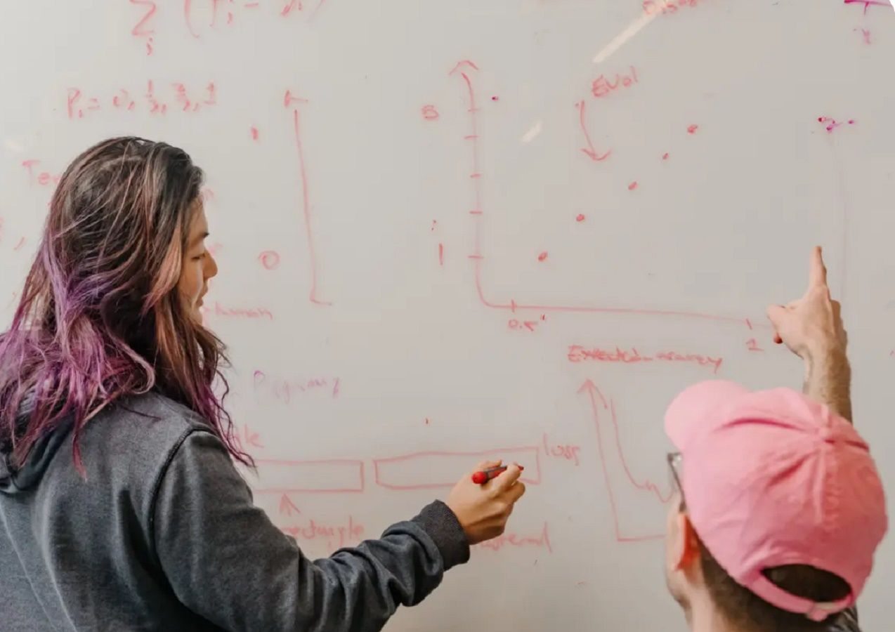 AI researchers at Anthropic addressing a whiteboard with charts and models