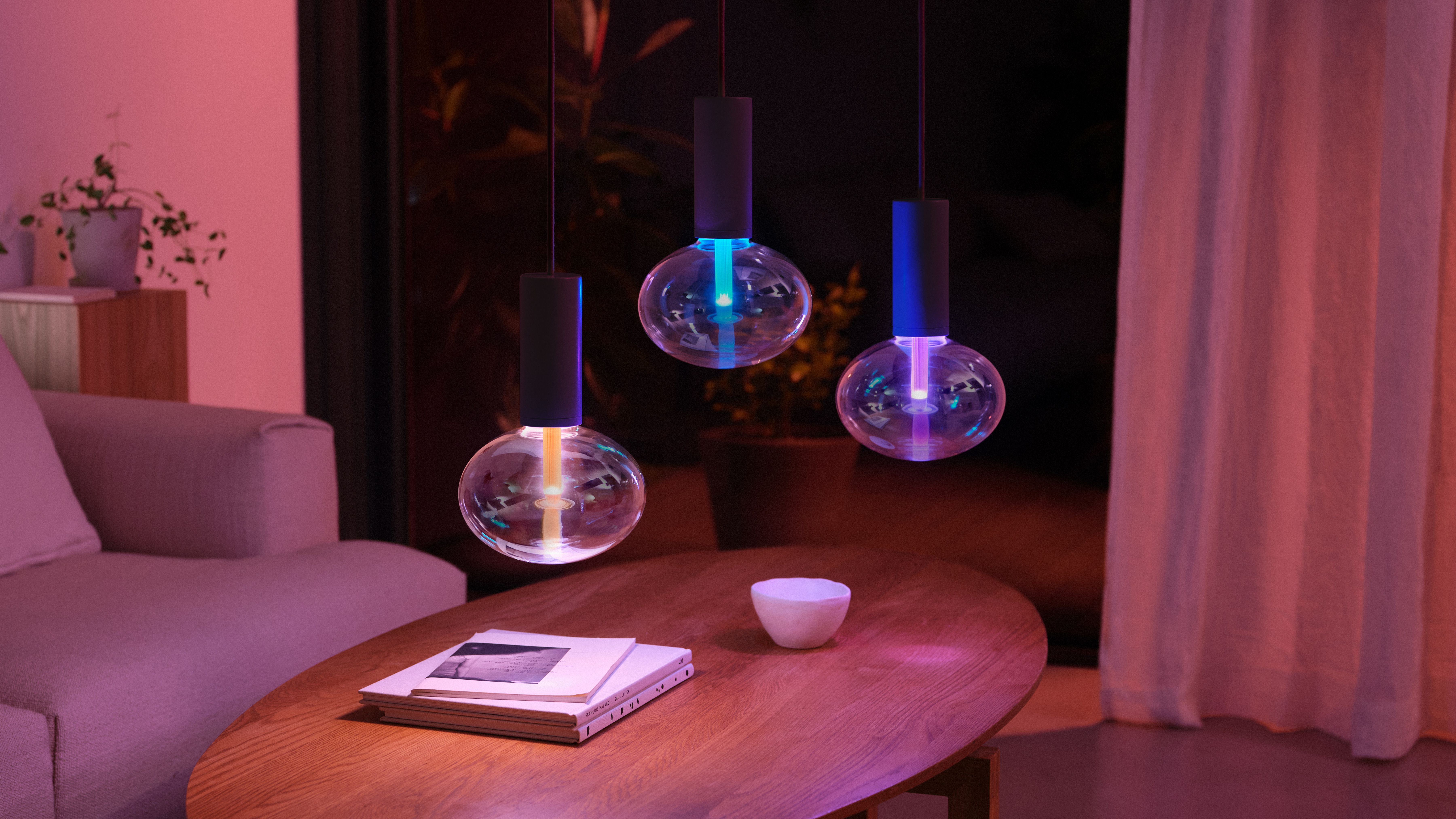 Three Philips Hue pendant lamps over a coffee table