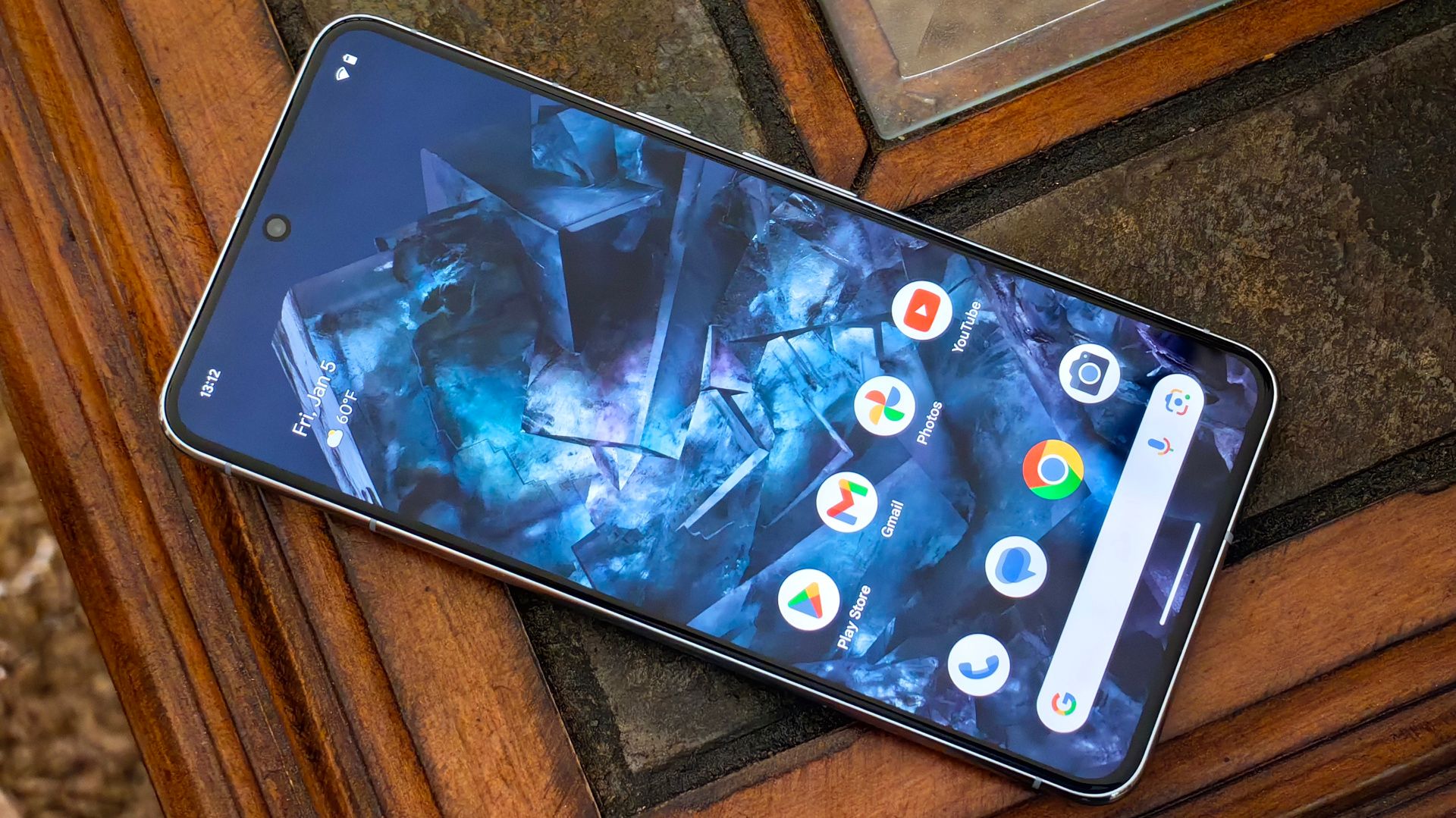 A Google Pixel 8 Pro with an illuminated display sits on a wooden table