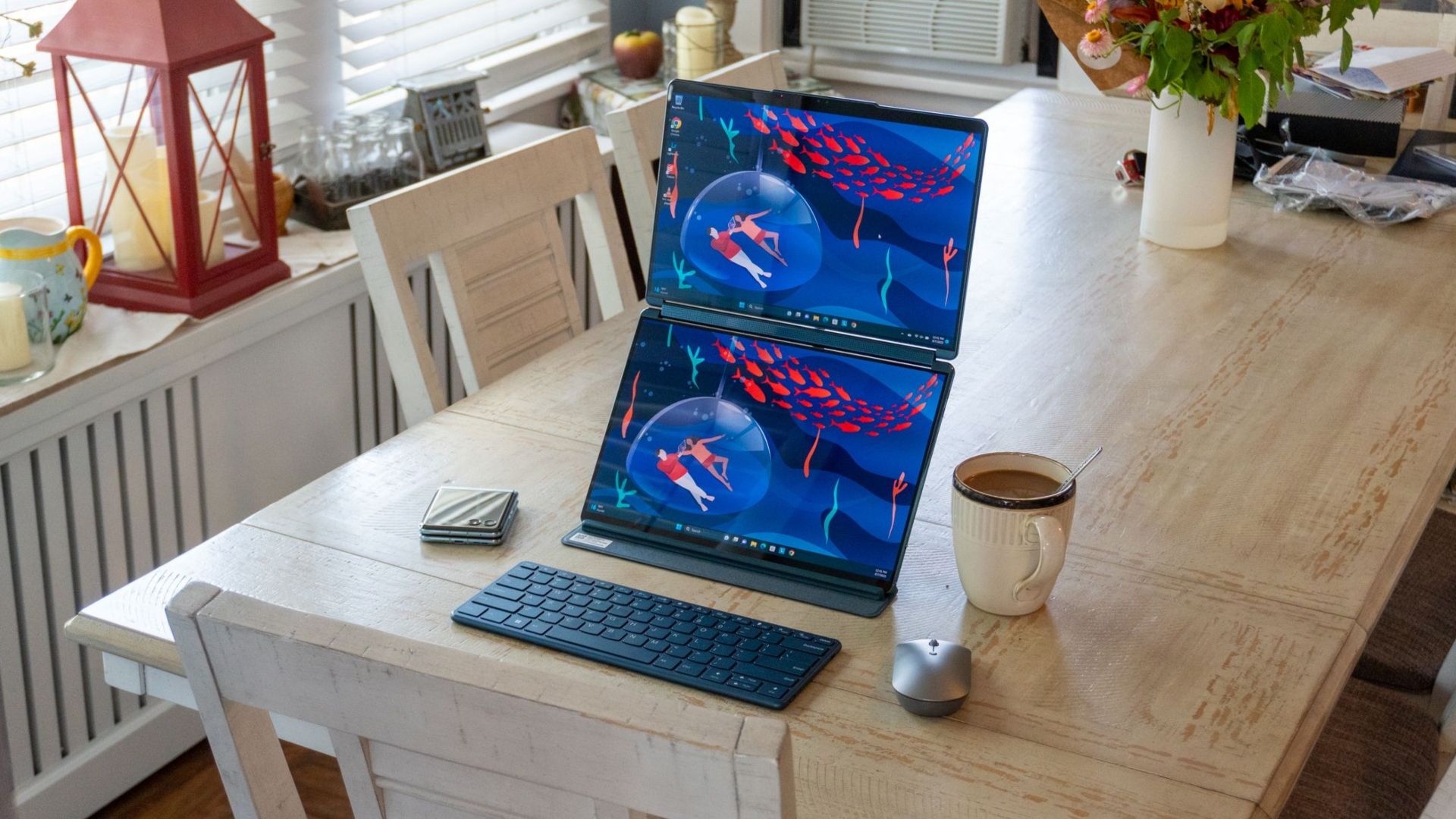 Lenovo Yoga Book on a table with a cup of tea, a mouse and a keyboard next to it