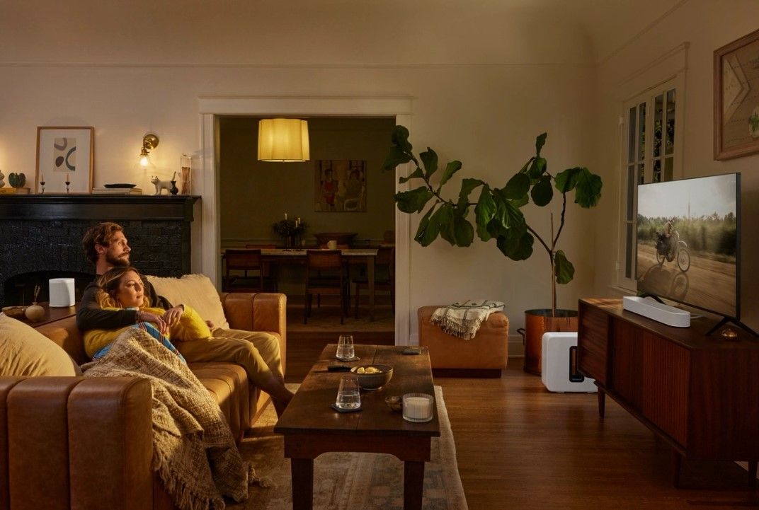 A couple watching TV, surrounded by Sonos speakers