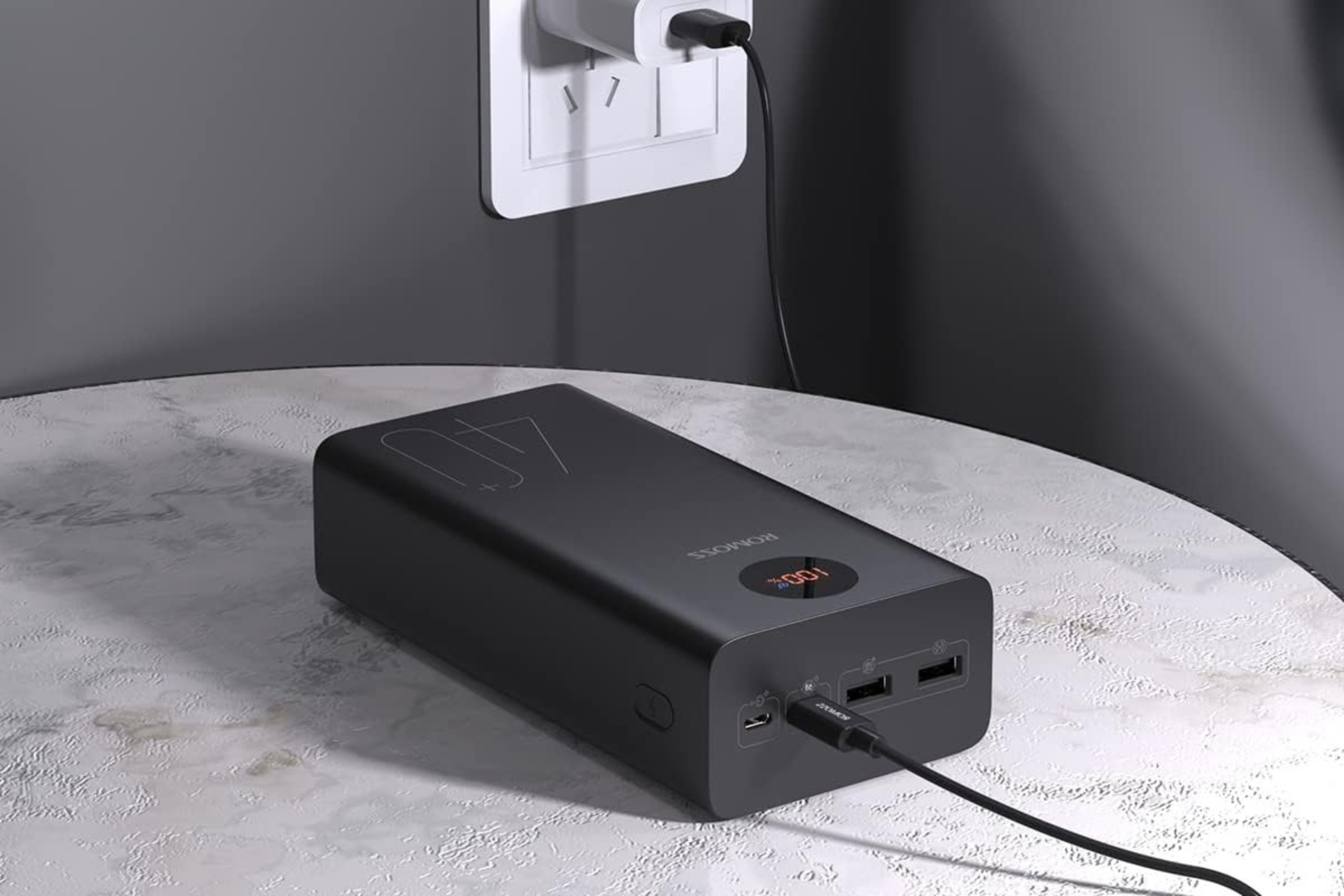 ROMOSS 40000mAh Portable Power Bank on table being charged
