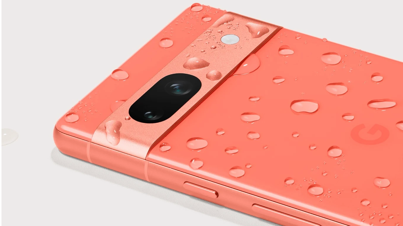 A coral Google Pixel 7a lying face down with water droplets on the backplate.